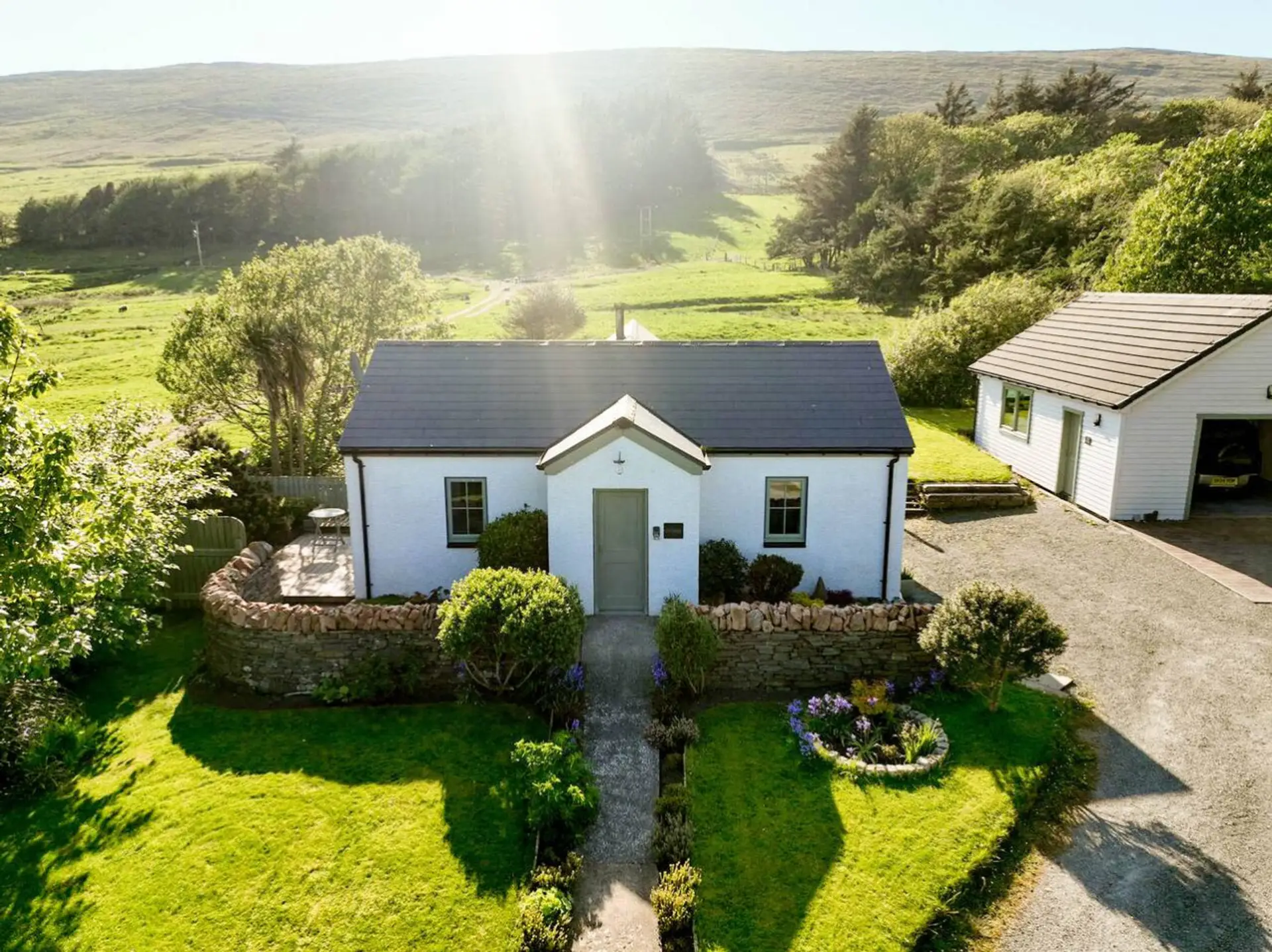 Front view of the cottage with private garden, driveway and detached garage.