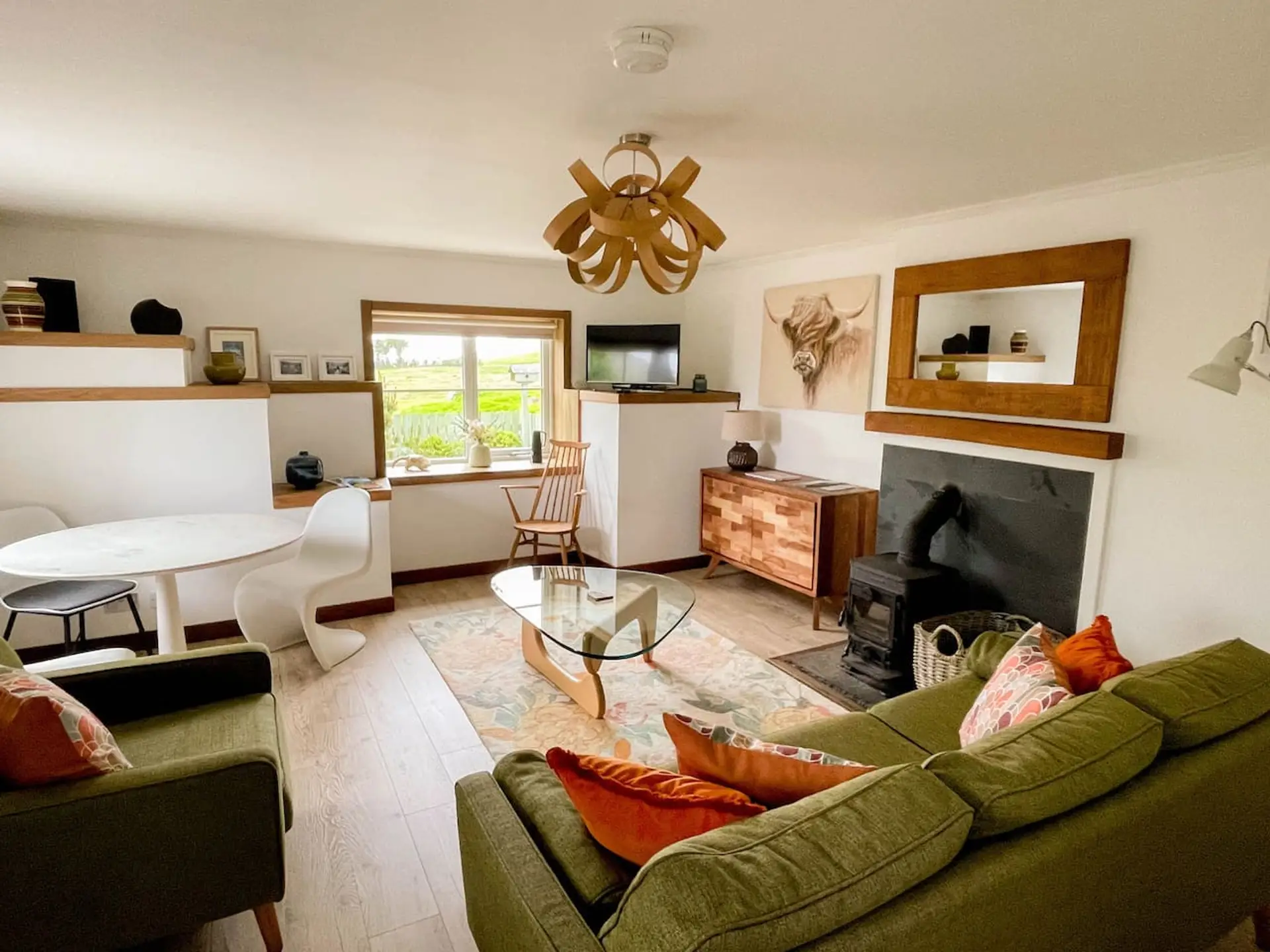 Open plan living and dining area with sofa, TV, and a log burner