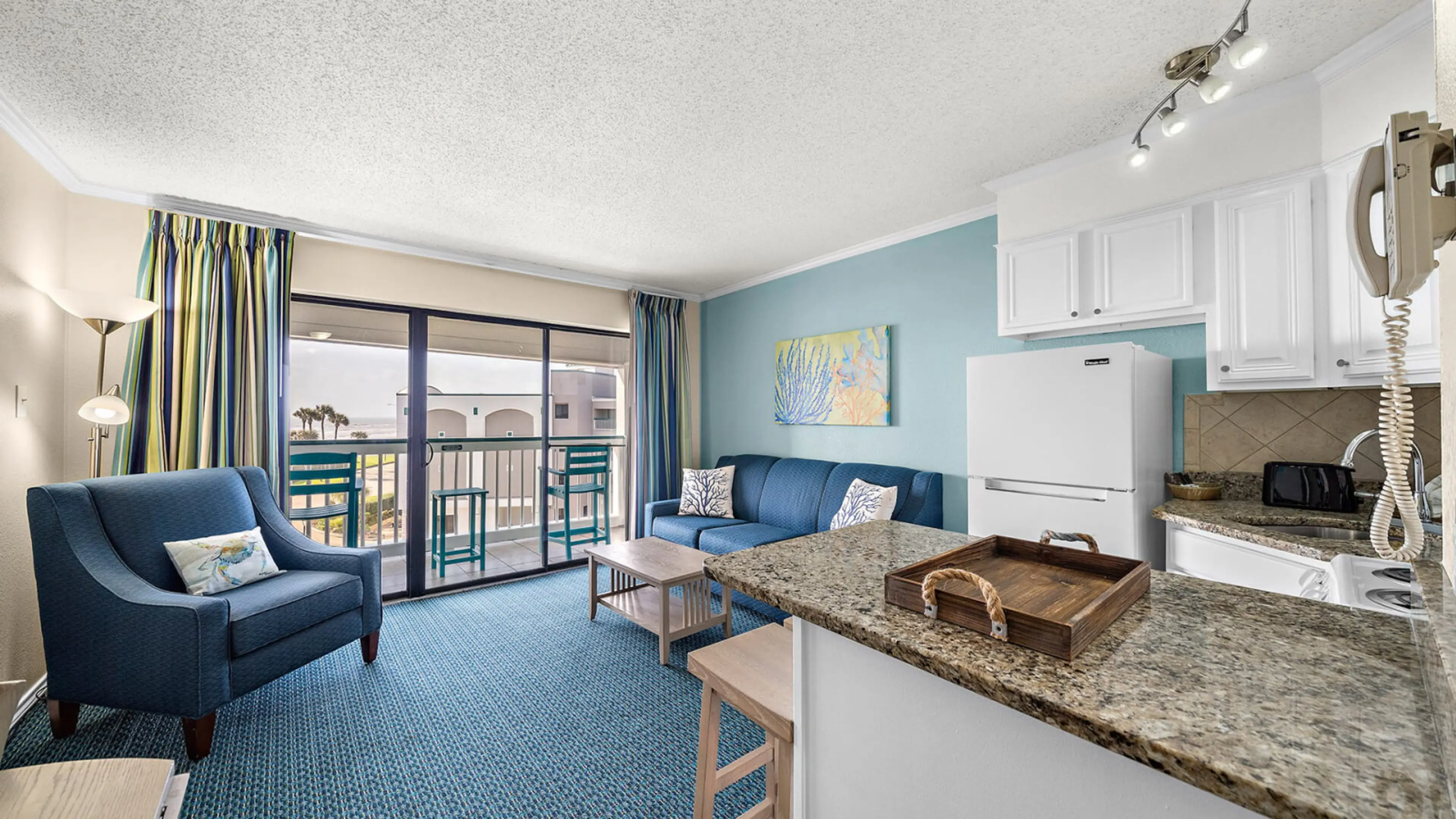 Full condo view from sliding glass door—see living, dining, kitchen, and hallway to front door