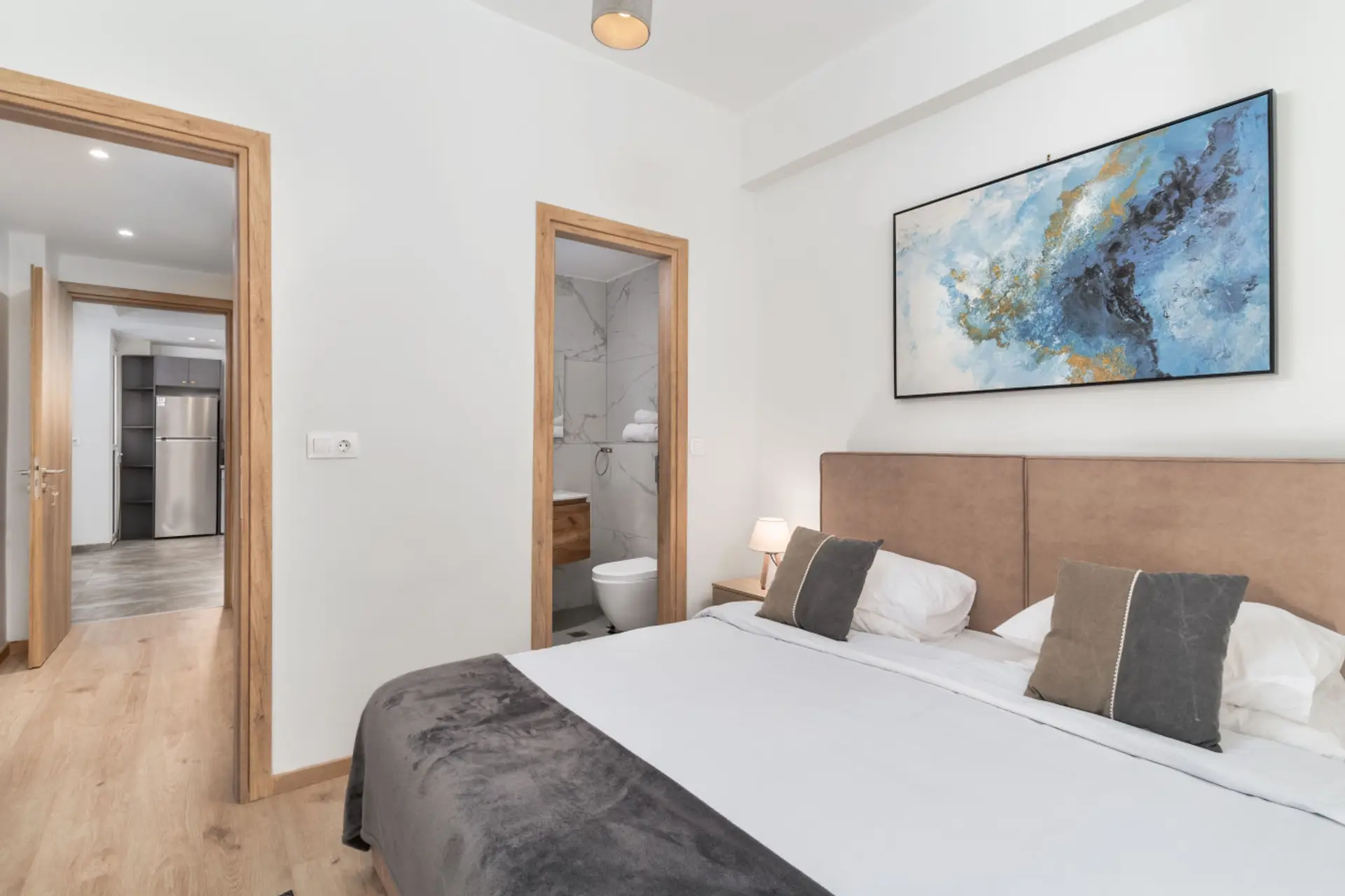 Elegant ensuite master bedroom featuring marble-accent bathroom access and a minimalist layout