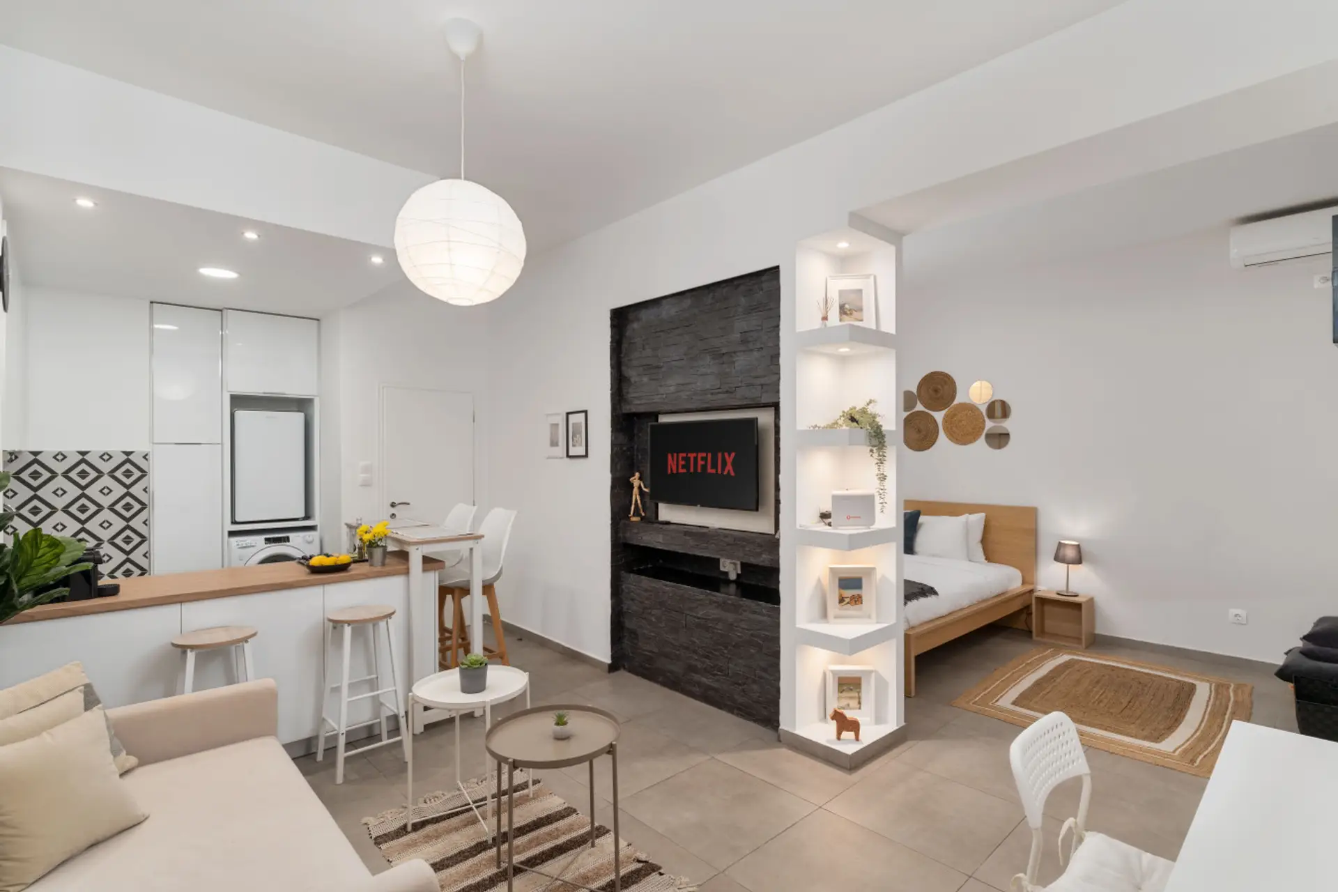 Modern open-plan living area with cozy sofa, smart TV, and breakfast bar connecting to the kitchen.