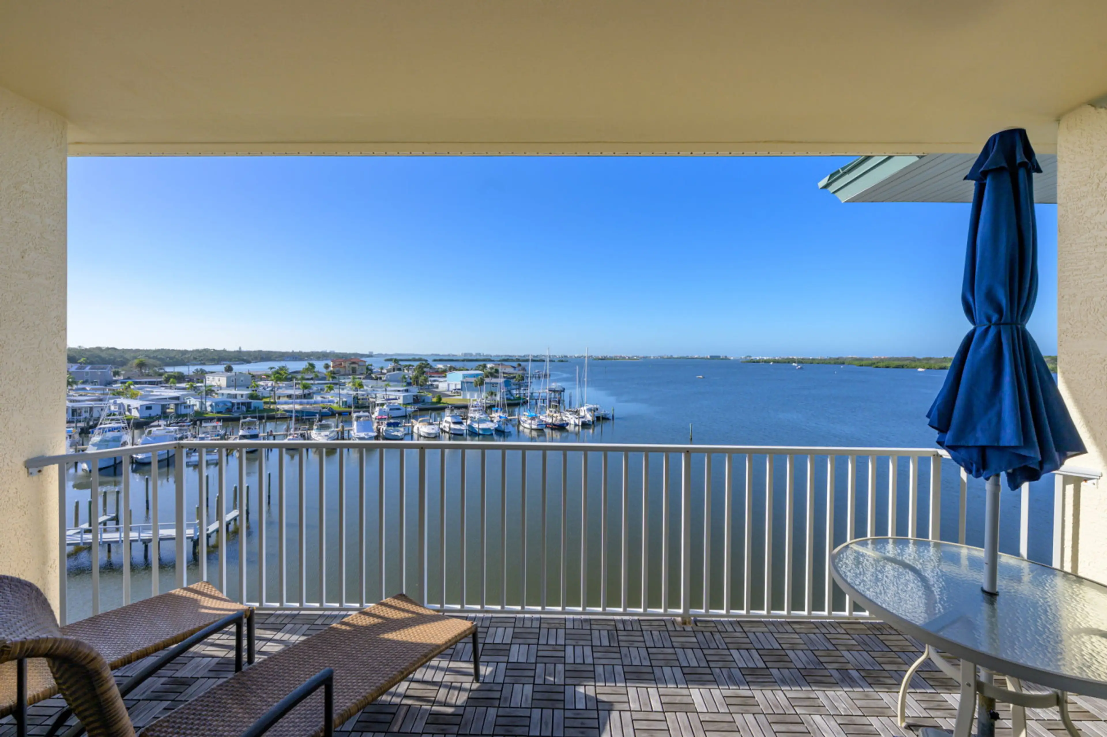 View from the private top-floor balcony overlooking Boca Ciega Bay and the marina, with water glistening in the sun and boats gently docked