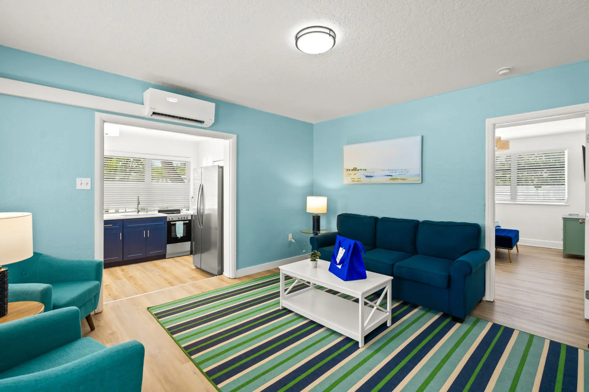Siesta Key seaside escape with teal seating, a beach-inspired rug, and an open kitchen—designed for effortless comfort and smooth coastal living.