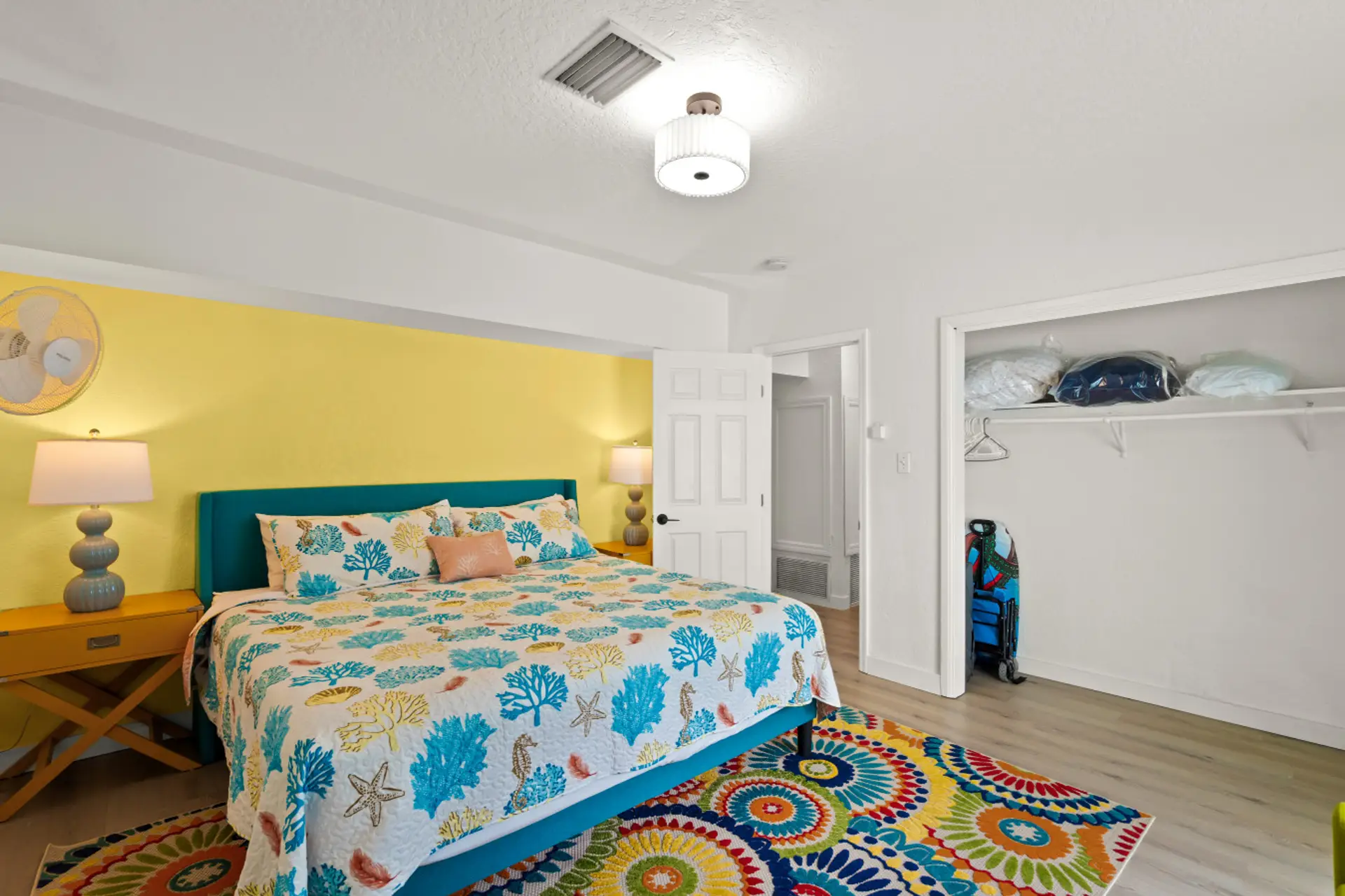 Siesta Key beach retreat master suite with coral linens, golden accents, and a whimsical rug—crafted for cheerful rest and effortless coastal charm.