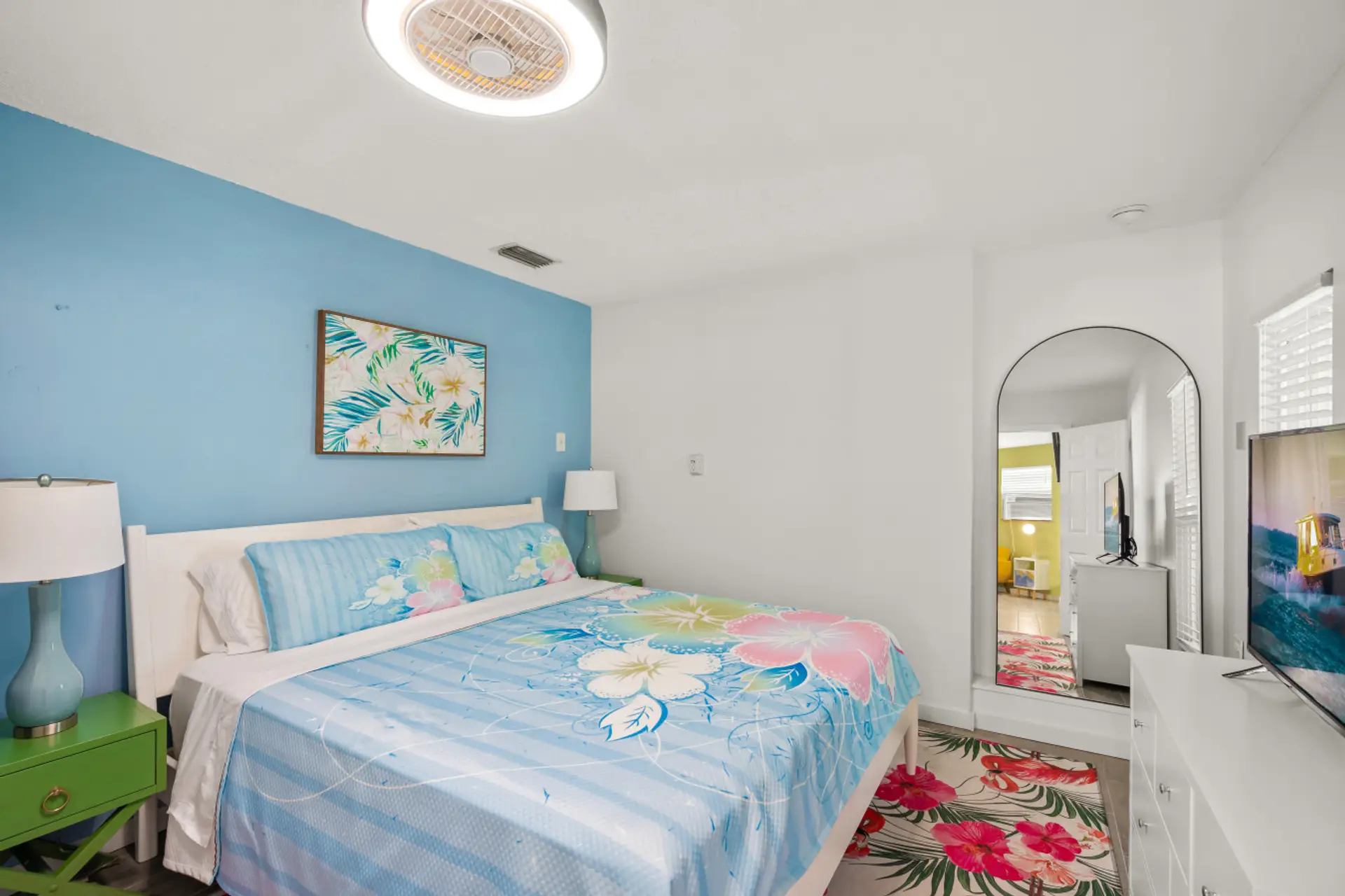 Siesta Key Beach bedroom with blue floral bedding, leafy artwork, and mirrored accents—perfect for a bright and relaxing stay.
