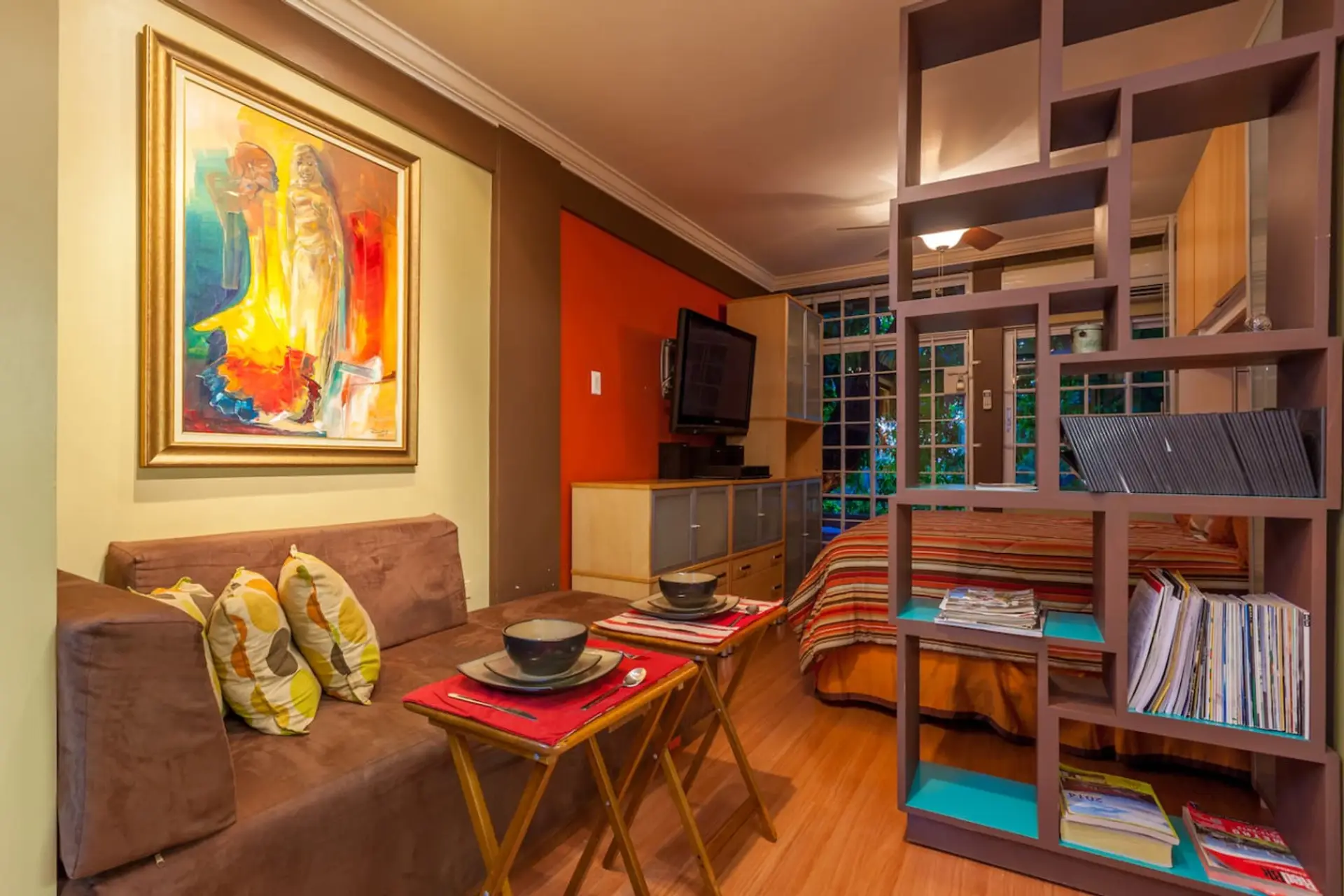 Colorful living room w/ cozy sofa, vibrant art & open shelving, a warm spot to relax after a day out