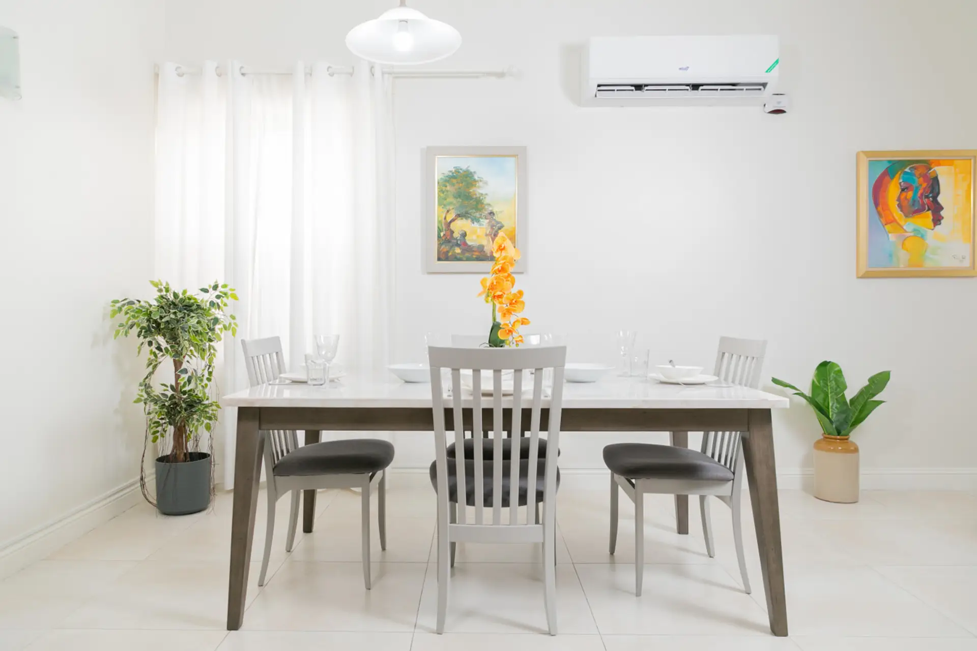Sun-filled dining area w/ white table, stylish chairs & greenery for relaxed meals together.