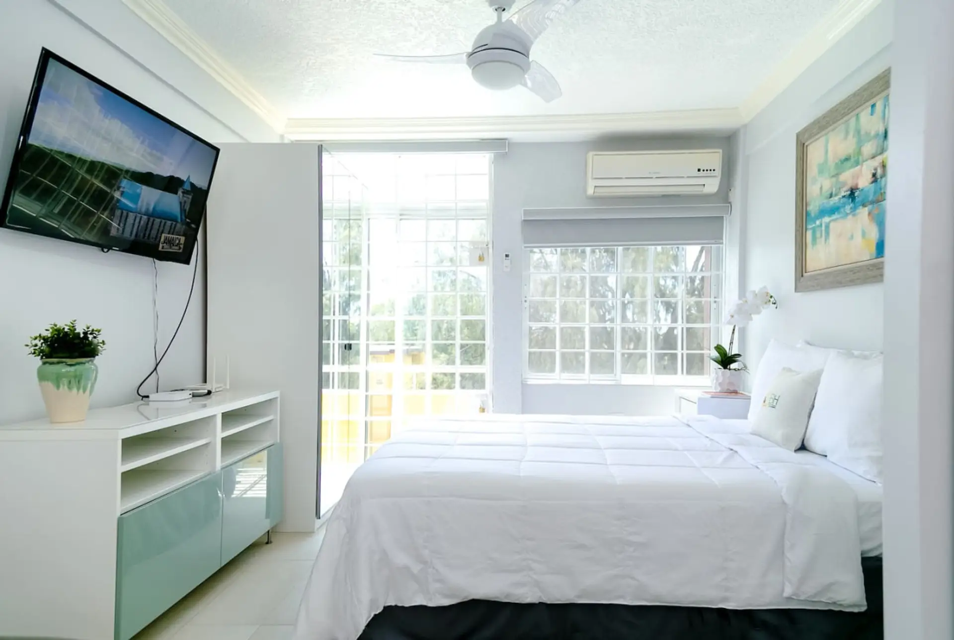 Airy bedroom w/ wall-mounted TV, AC & French doors opening to a bright balcony