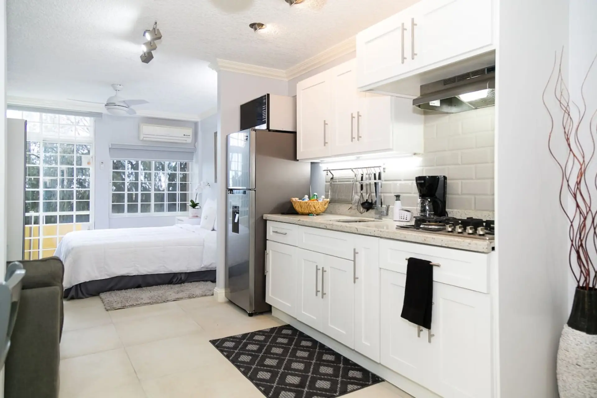Bright studio w/ compact kitchen, white cabinetry & comfy bed near sunlit French doors