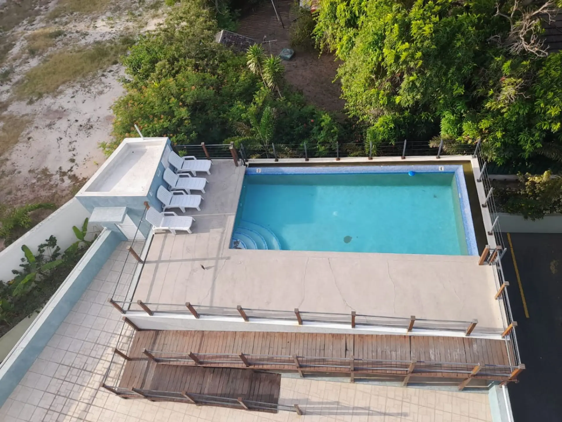 Rooftop pool w/ lounge chairs & surrounding greenery—perfect for a refreshing dip or relaxing under the sun
