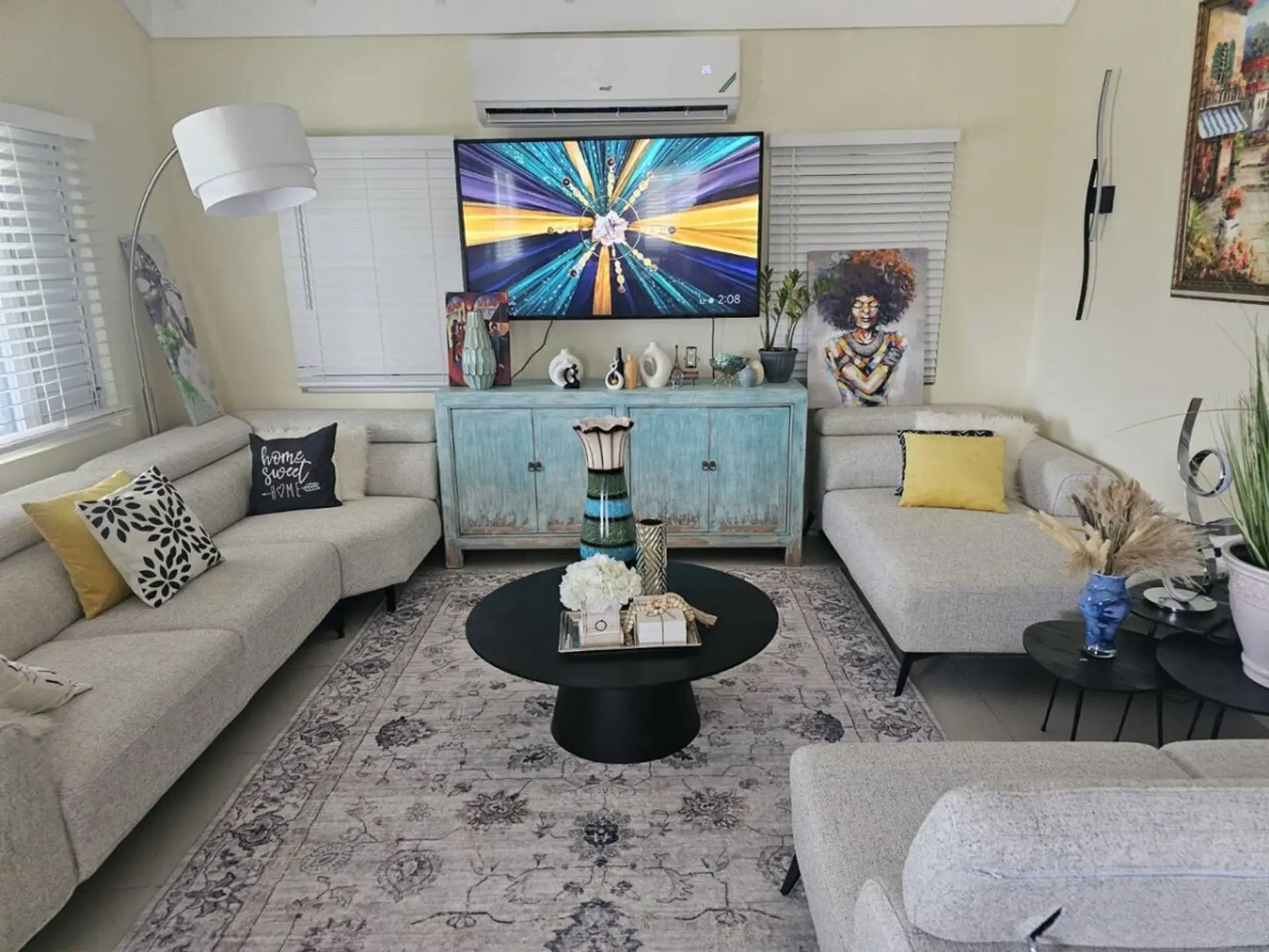 Bright living room w/ comfy sectional, colorful art, and TV—perfect for relaxing after a day out.
