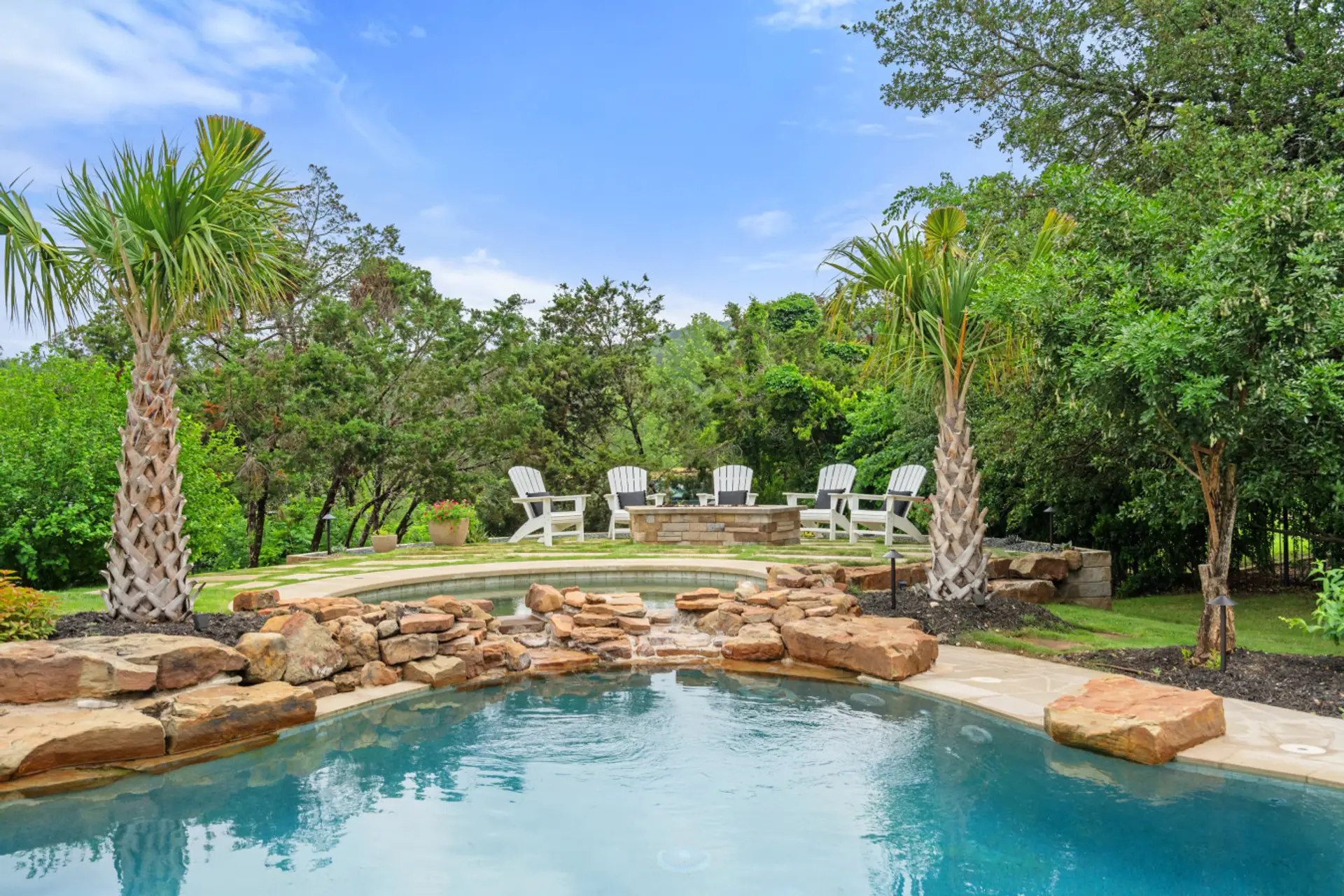 Resort-style pool with waterfall and fire pit seating.