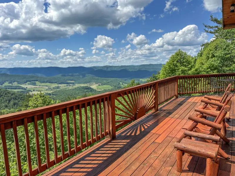 Cloud 9's wraparound deck with log chairs and long-range mountain views