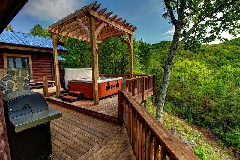 Pergola-covered hot tub and gas grill on the wraparound deck