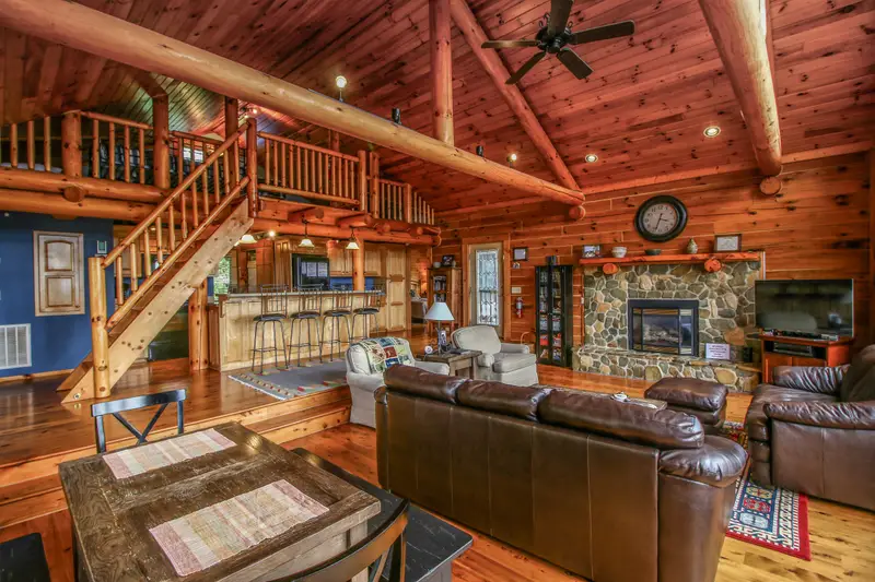 Open living area with stone gas fireplace and custom loft staircase