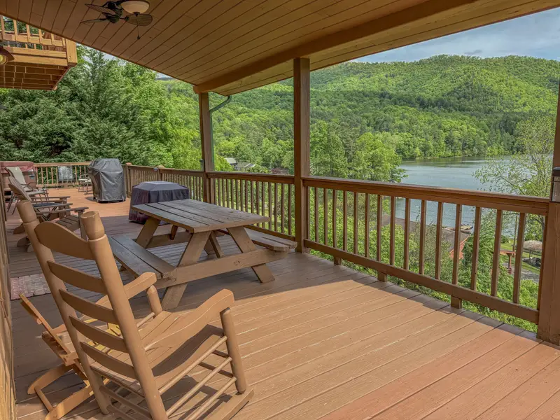 Covered wraparound deck with rocking chairs and a picnic table above Watauga Lake