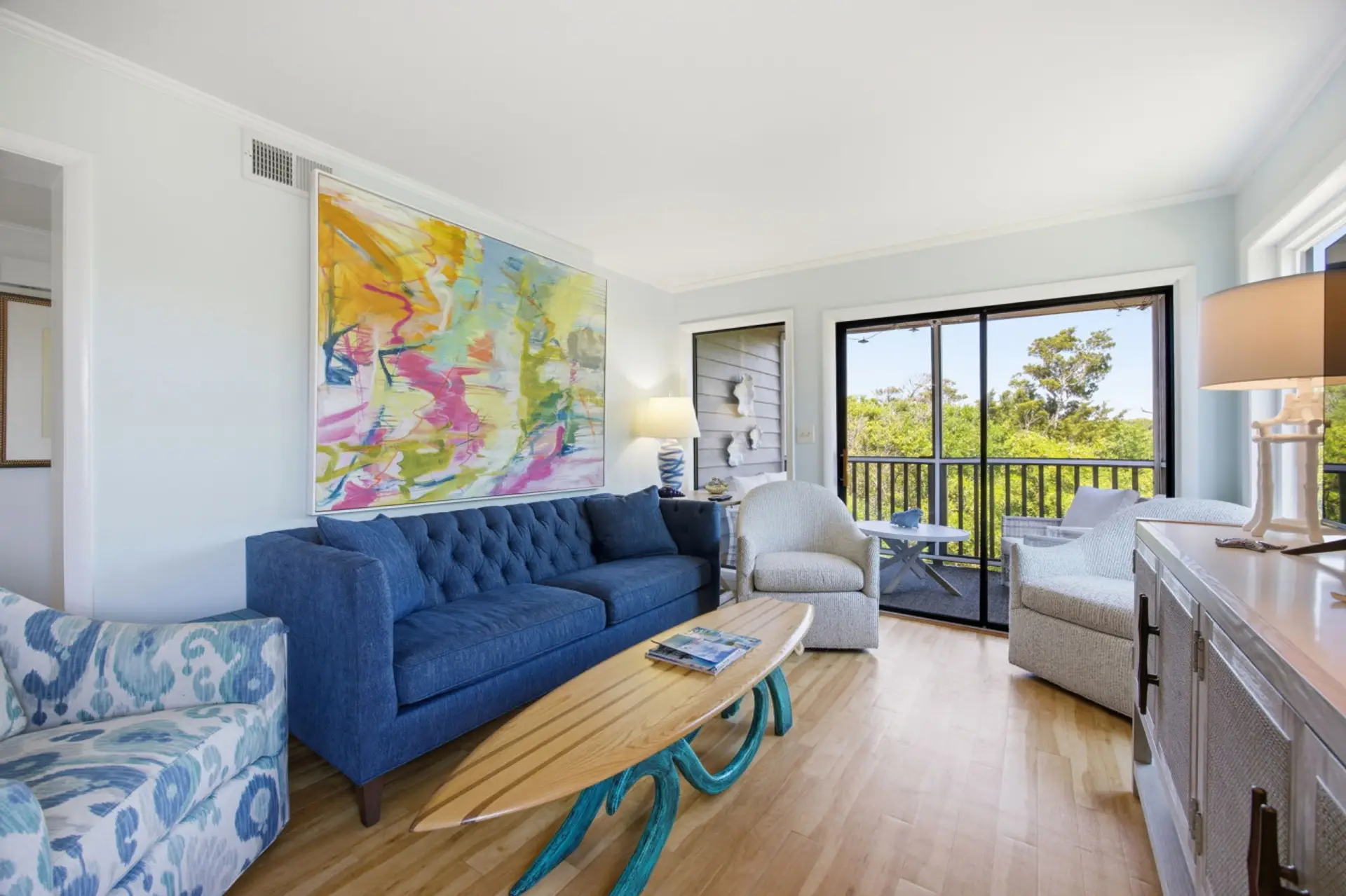 Relax in this bright coastal living room with cozy seating and peaceful balcony views