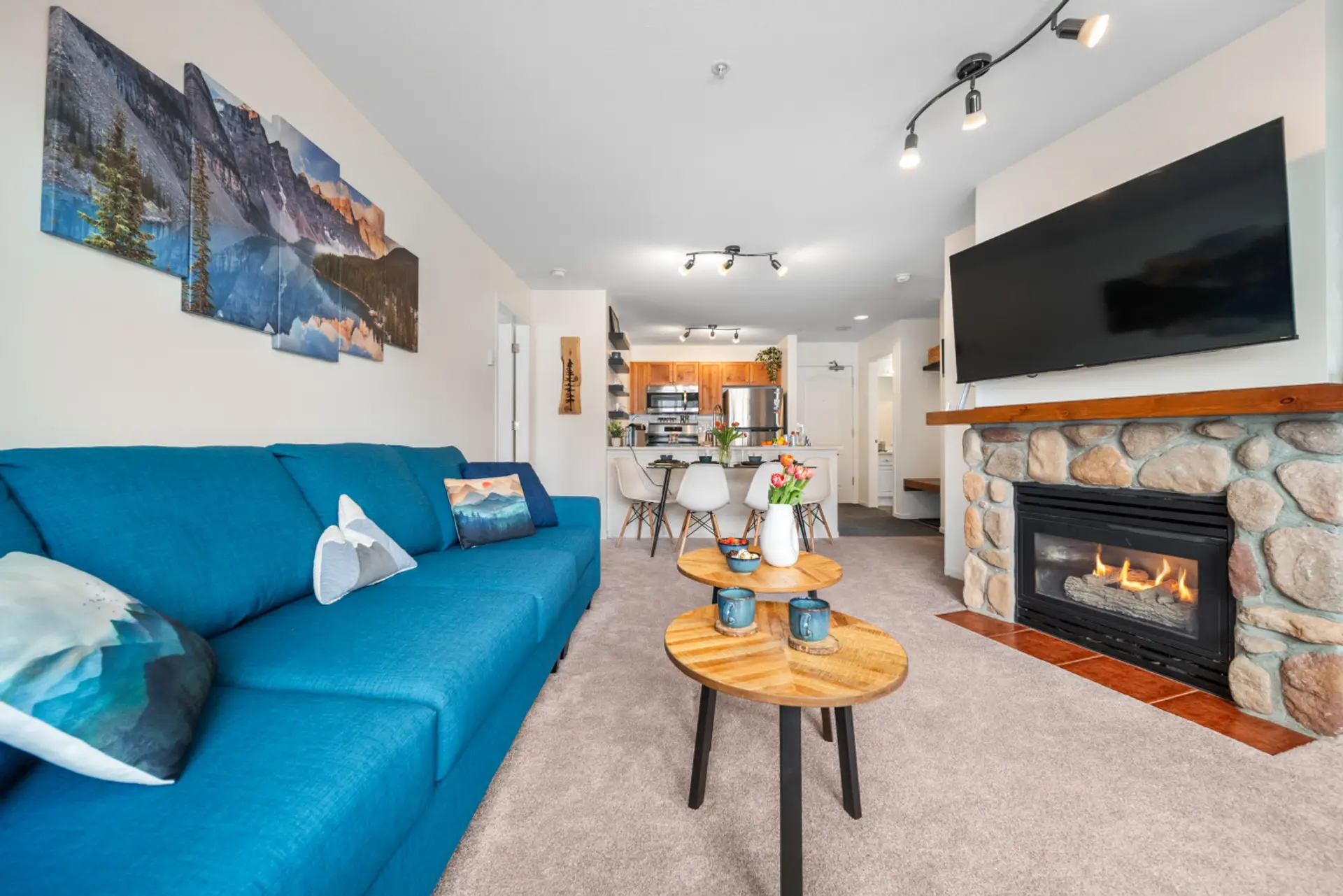 Whistler Village open-concept living room with gas fireplace, large TV, queen sofa bed, dining area, and full kitchen — ideal for relaxing after skiing, biking, or exploring Whistler.