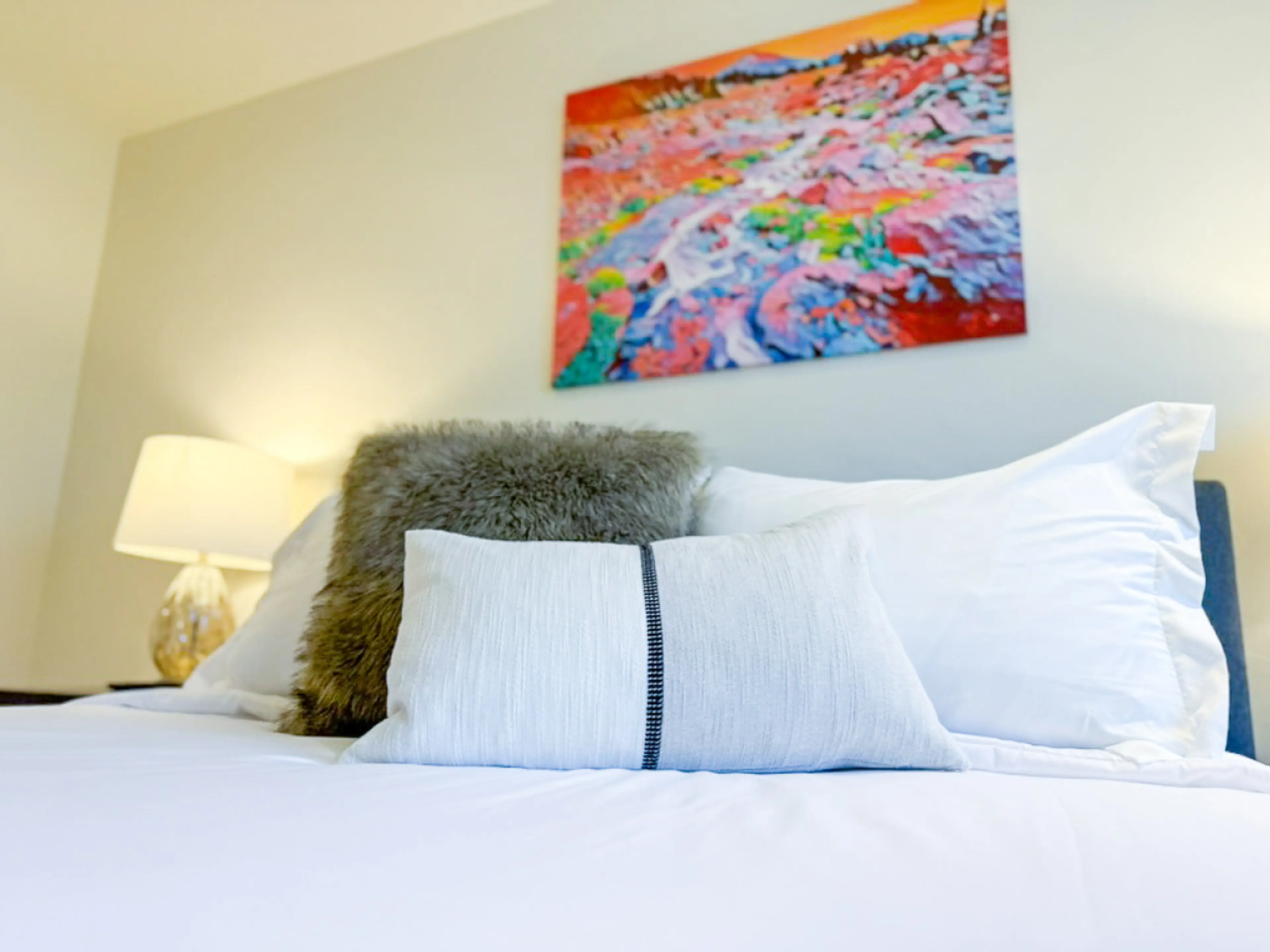 Bright and inviting guest bedroom with a plush queen bed, soft accent pillows, and local artwork to complete the cozy retreat.
