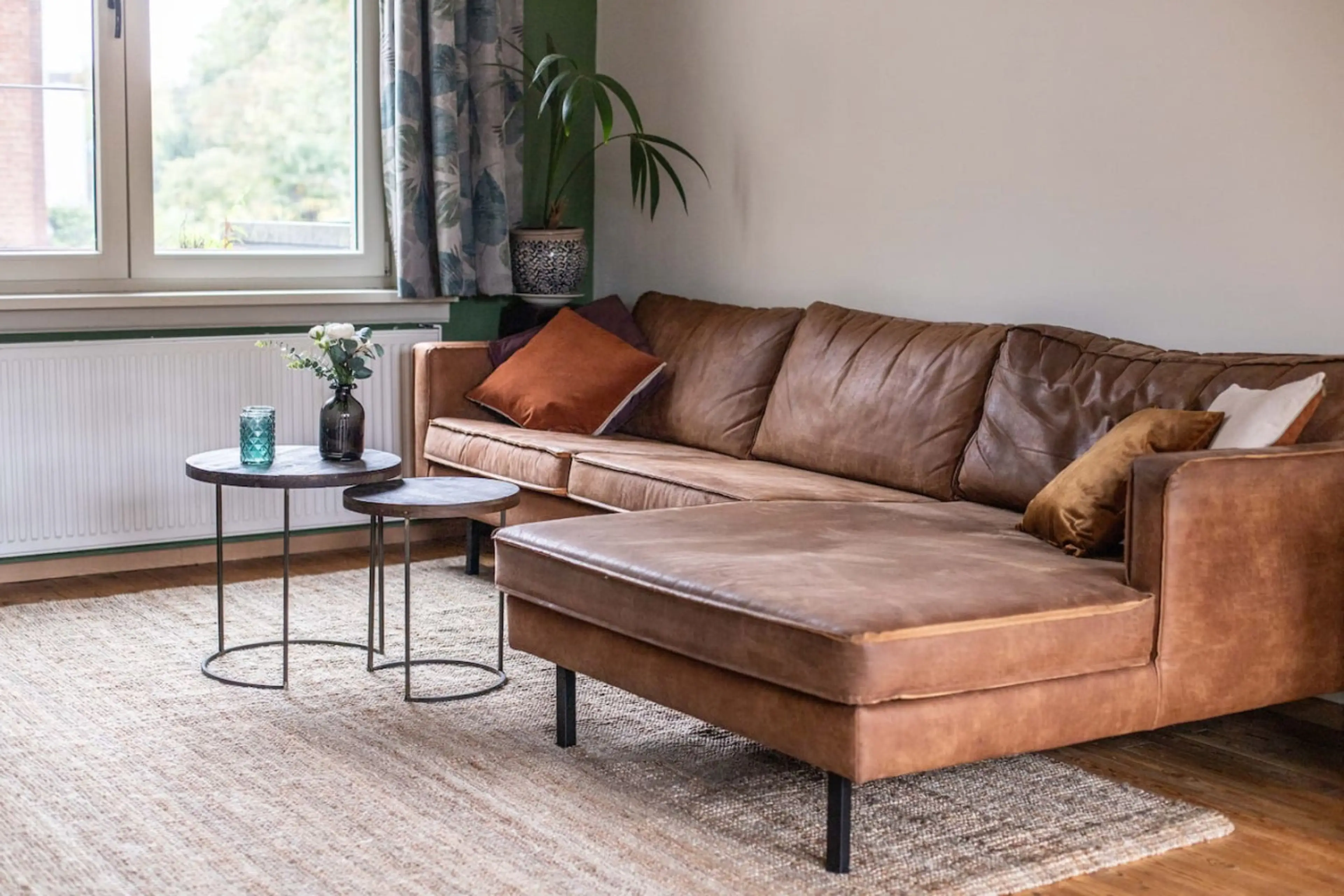 Cozy living area w/ leather sofa & soft natural light, perfect for relaxing after a day out