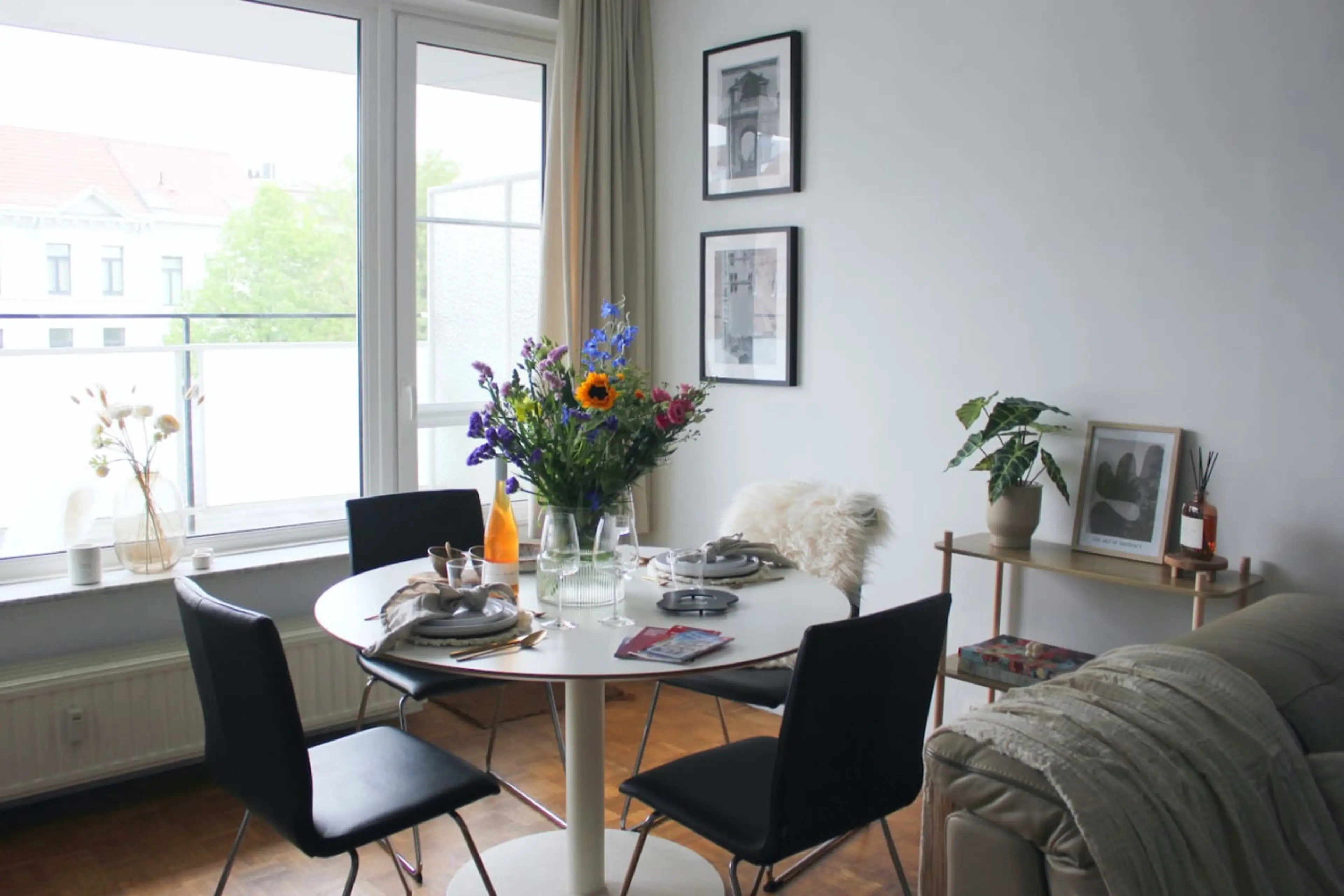 Bright dining area w/ round table, fresh flowers & large windows letting in natural light