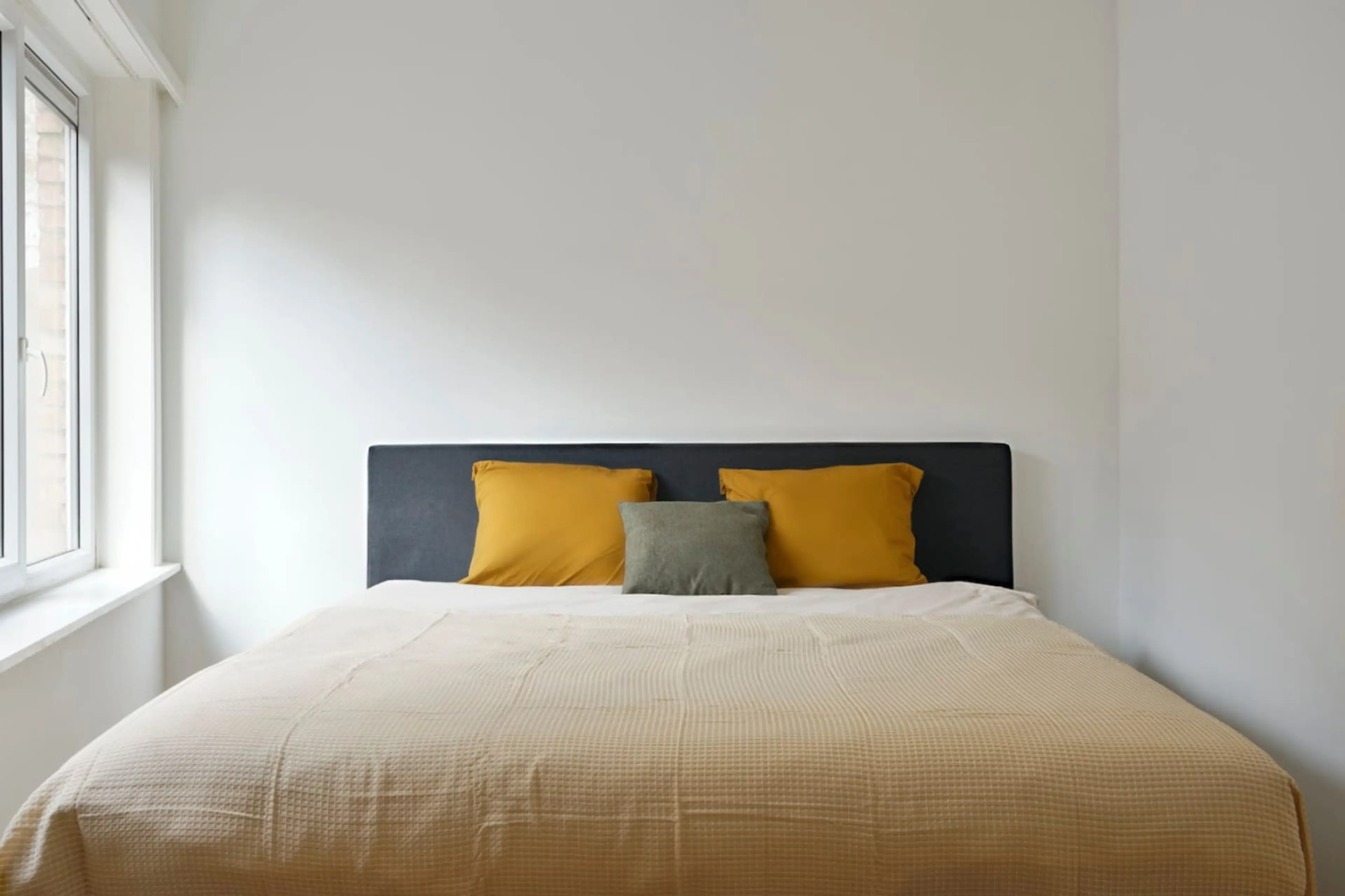 Cozy bedroom w/ soft bedding, accent pillows & window light creating a calm, restful feel