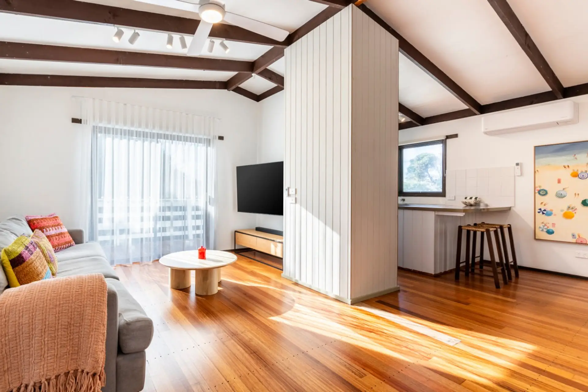 Bright open-plan living space with a comfortable lounge, breakfast bar, and abundant natural light
