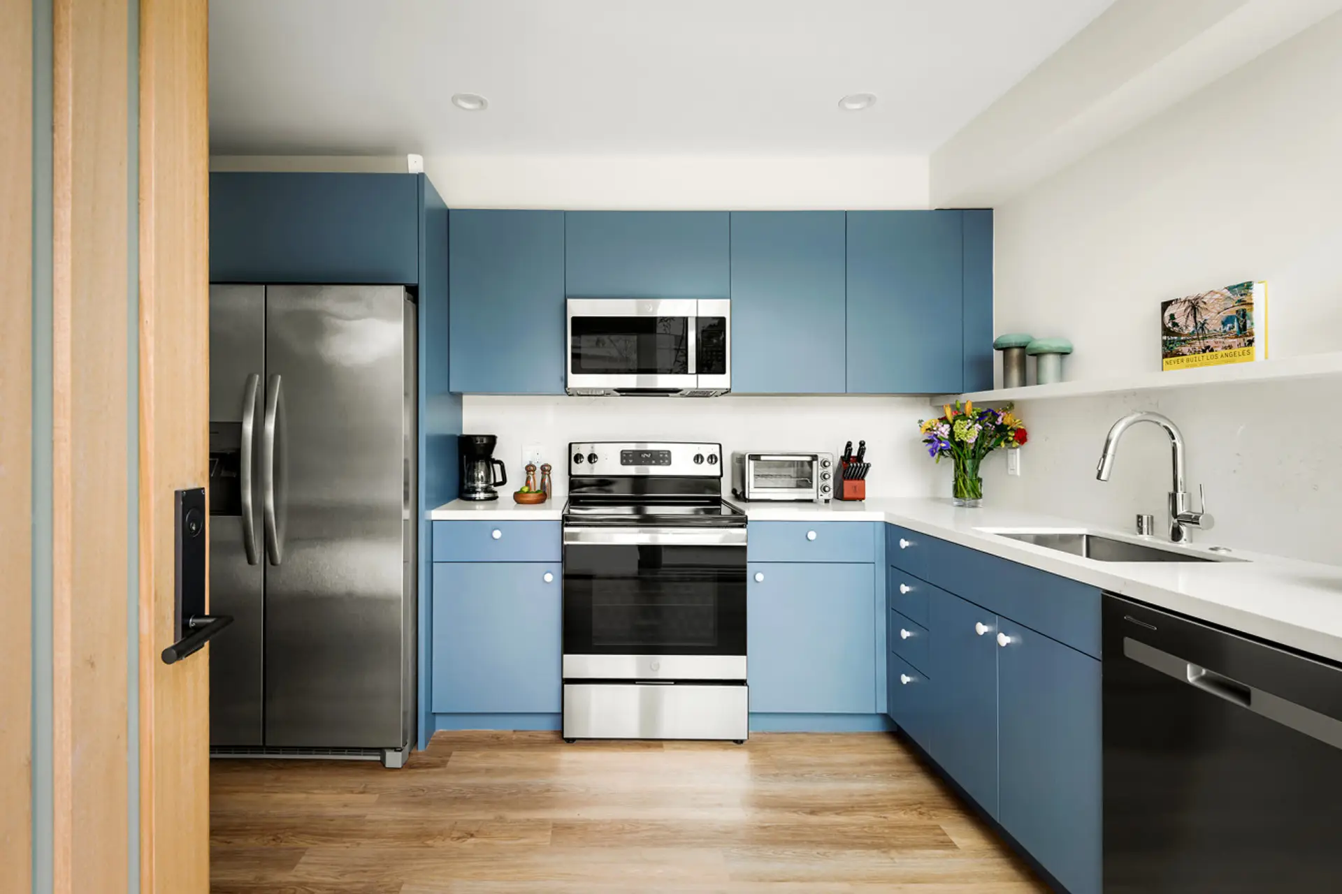 Modern blue cabinetry meets stainless steel appliances in this bright, functional kitchen.