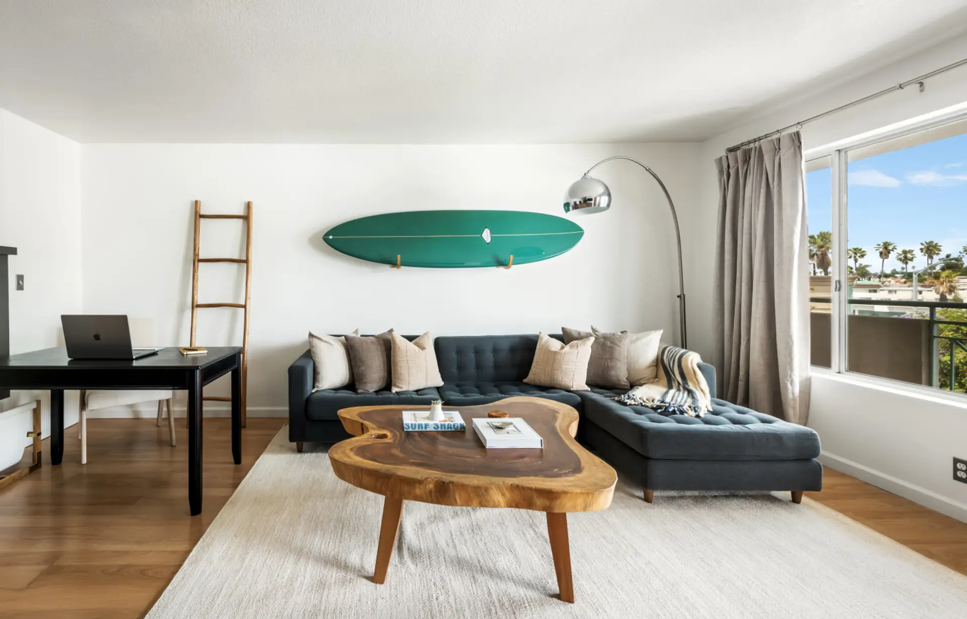 Coastal charm meets comfort—relax in a stylish living room with surf-inspired decor and a natural wood centerpiece.