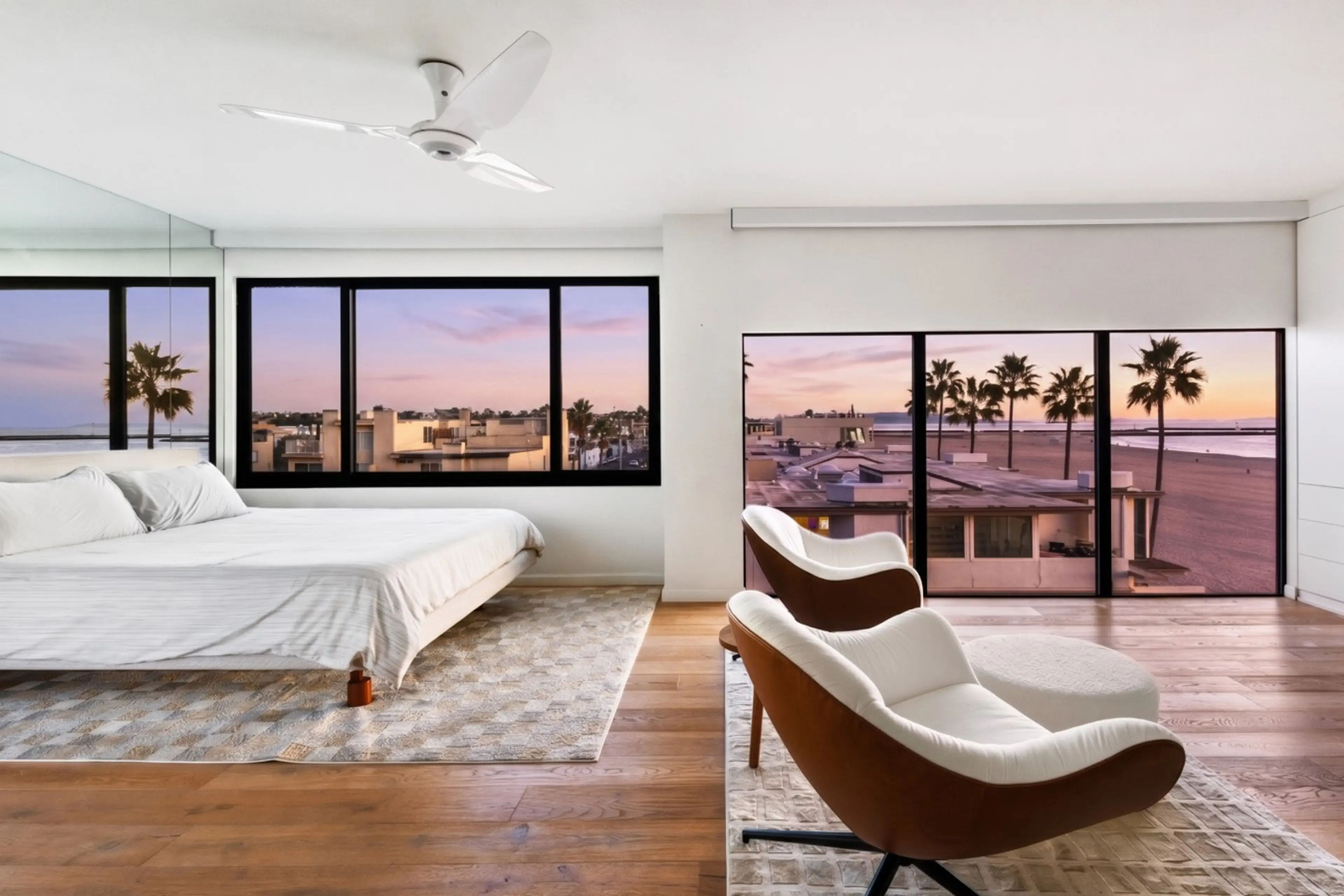 Bright primary bedroom with ocean views, featuring a comfortable king bed and floor-to-ceiling windows.