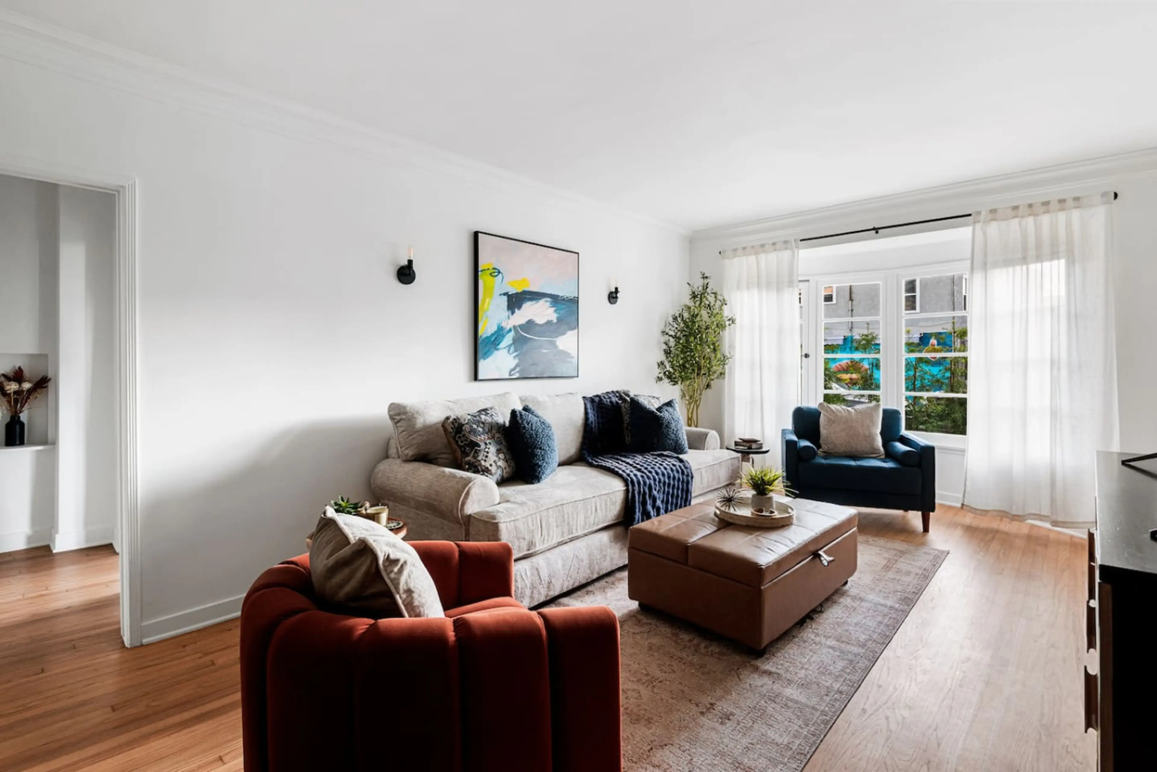 Airy living space featuring a cozy sofa, expansive window, and flowing white curtains.