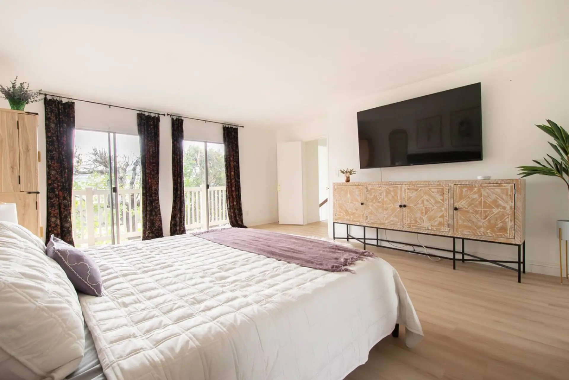 Relax in this bright bedroom featuring a comfortable king bed, large TV, and natural light.