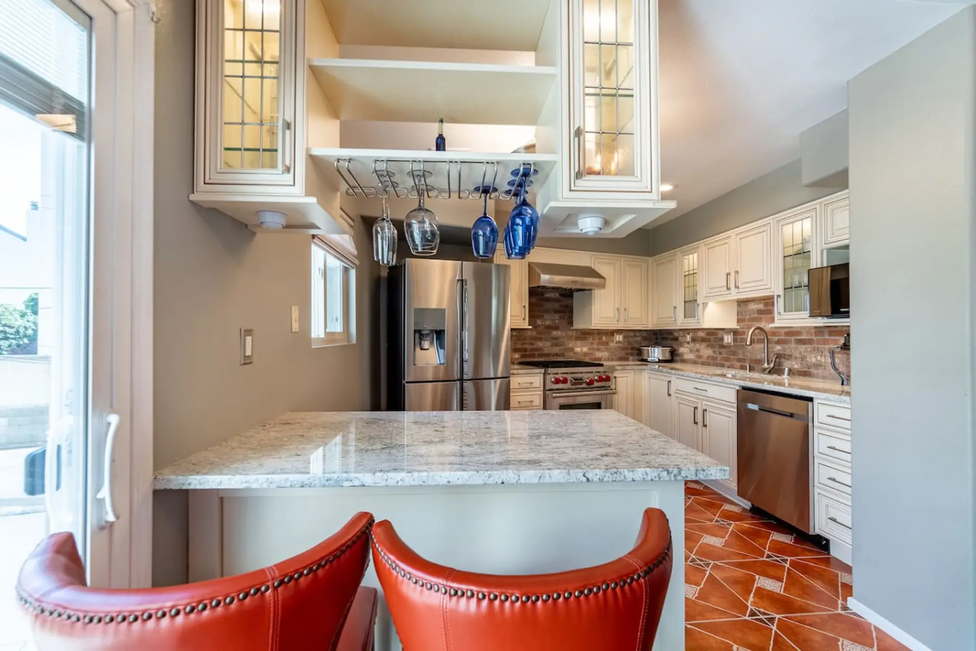 Cook and gather in this gorgeous chef's kitchen featuring a large granite island, stainless steel appliances, brick backsplash, and plenty of cabinet space for everything you need.