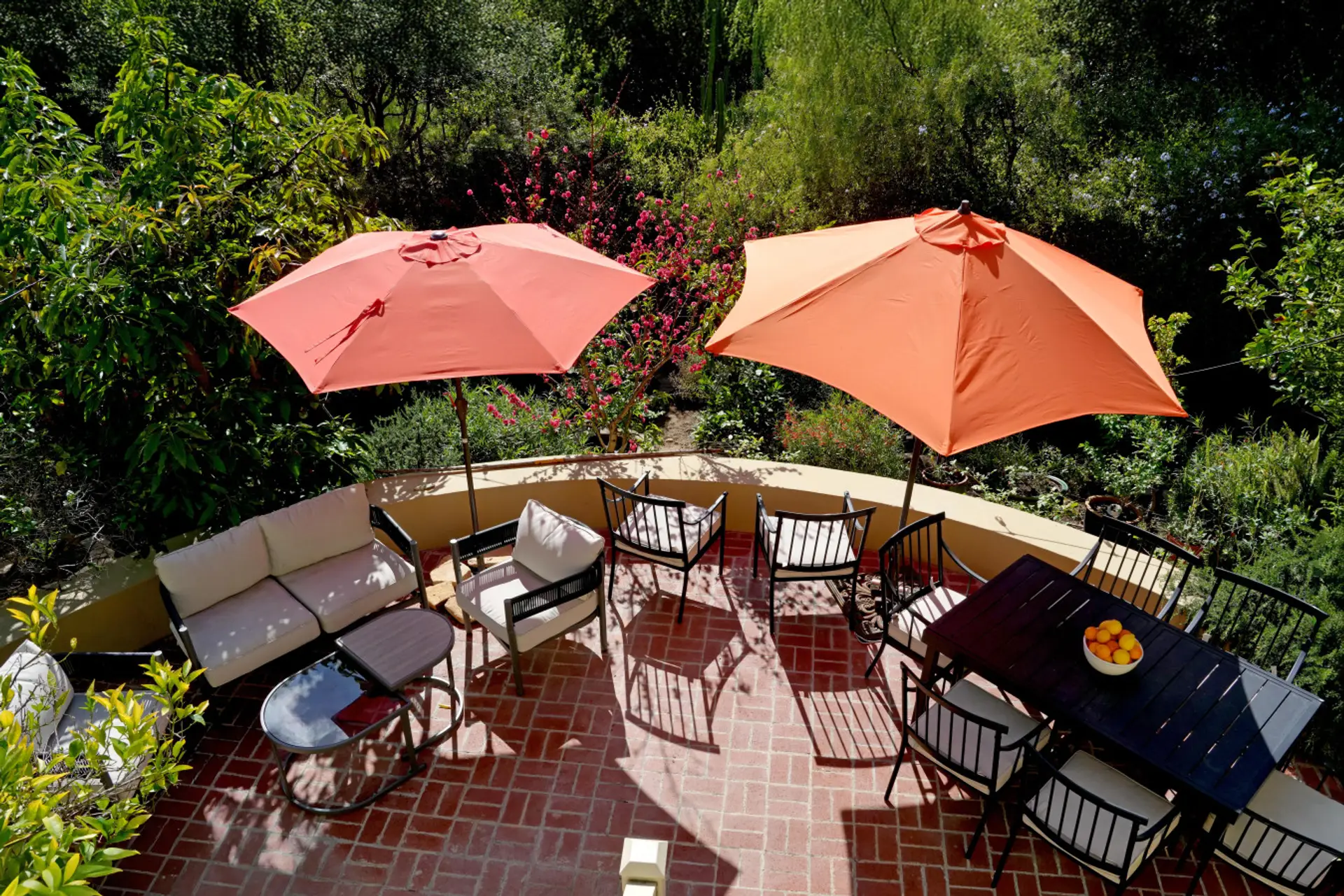 Lush, fully furnished garden patio with multiple seating zones and shade umbrellas — ideal for dining, lounging, or simply taking in the surroundings.