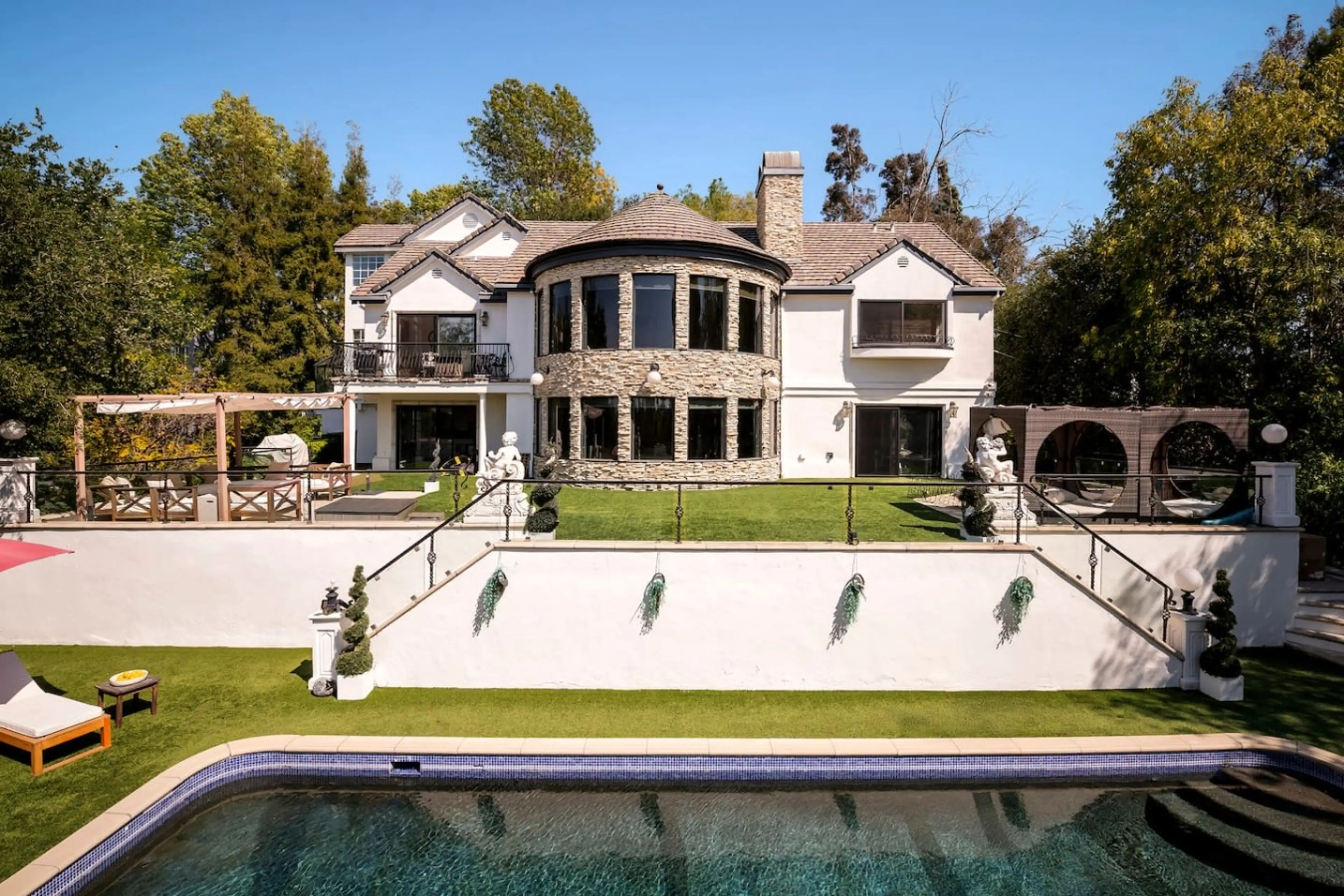 Gated European-style estate with stone detailing, bay windows, and resort-style grounds in Woodland Hills.