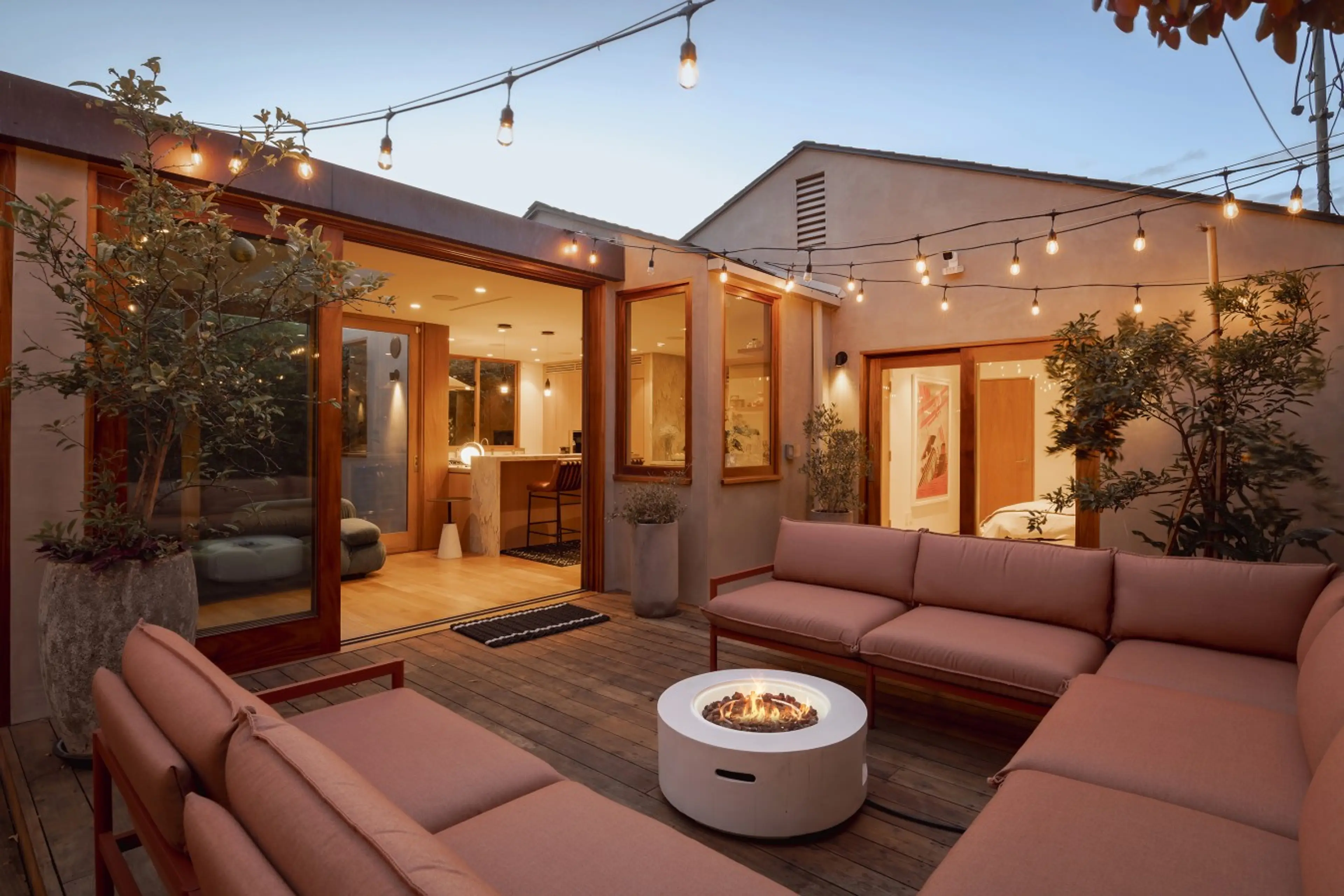 Unwind in the open-air backyard lounge, where string lights, a firepit, and seamless indoor-outdoor flow set the tone for easy Venice evenings.