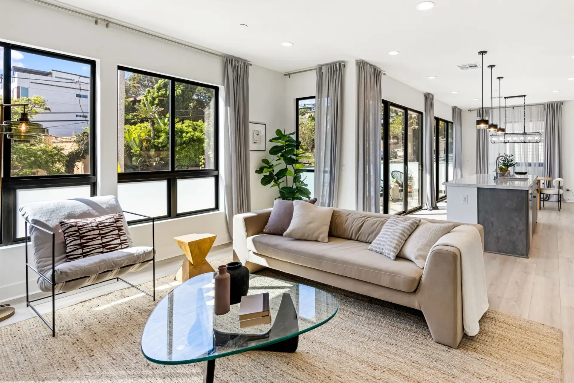 Sunlit living room with floor-to-ceiling windows and a comfortable neutral sofa, the perfect spot to unwind after a day exploring Echo Park.