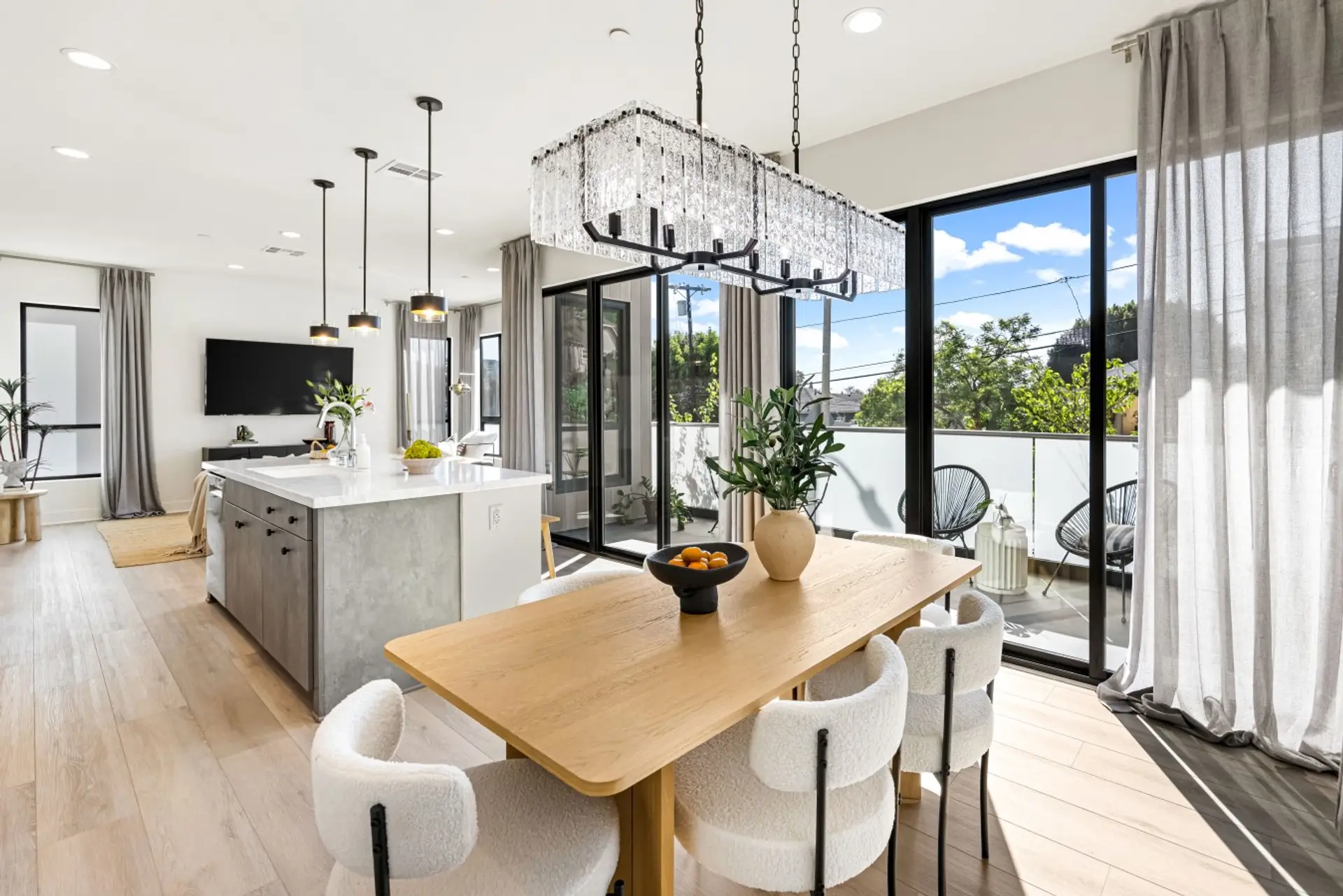 Open dining space beneath a statement chandelier, flowing right out to the balcony for easy indoor-outdoor living.