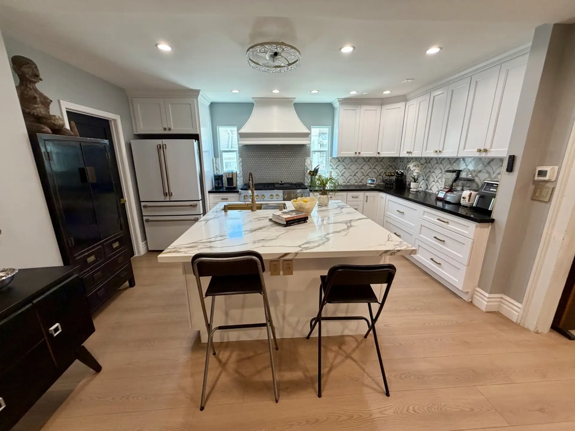 The stunning chef's kitchen is the heart of the home, featuring dramatic black cabinetry, elegant gold hardware, and a spacious island that's perfect for cooking, gathering, or entertaining. Thoughtfully designed with both style and functionality in mind,