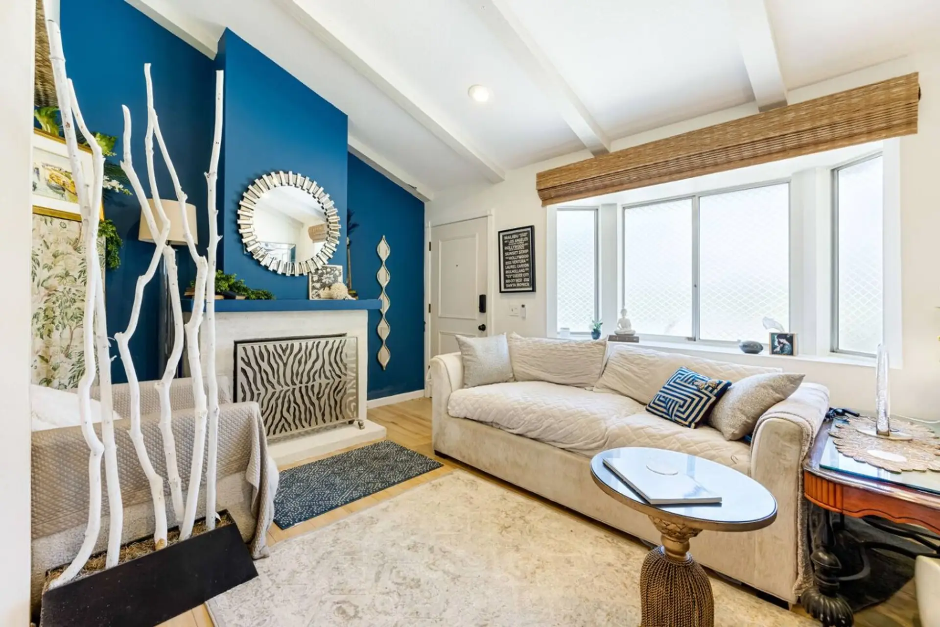 A calm, considered living room anchored by a freshly painted white fireplace surround and a patterned carpet with a subtle wave effect