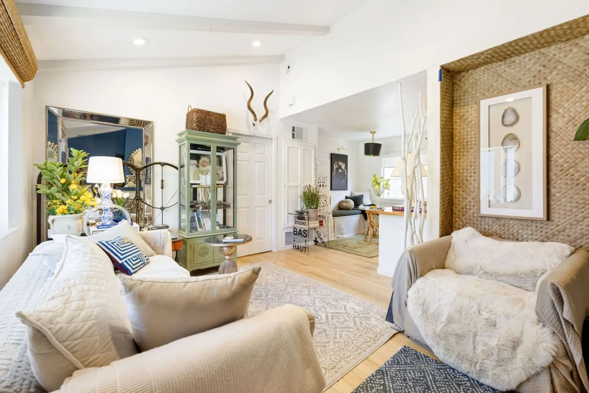 Vaulted ceilings with architectural beam accents, a cream sofa, and bay windows that flood the space with natural light all day