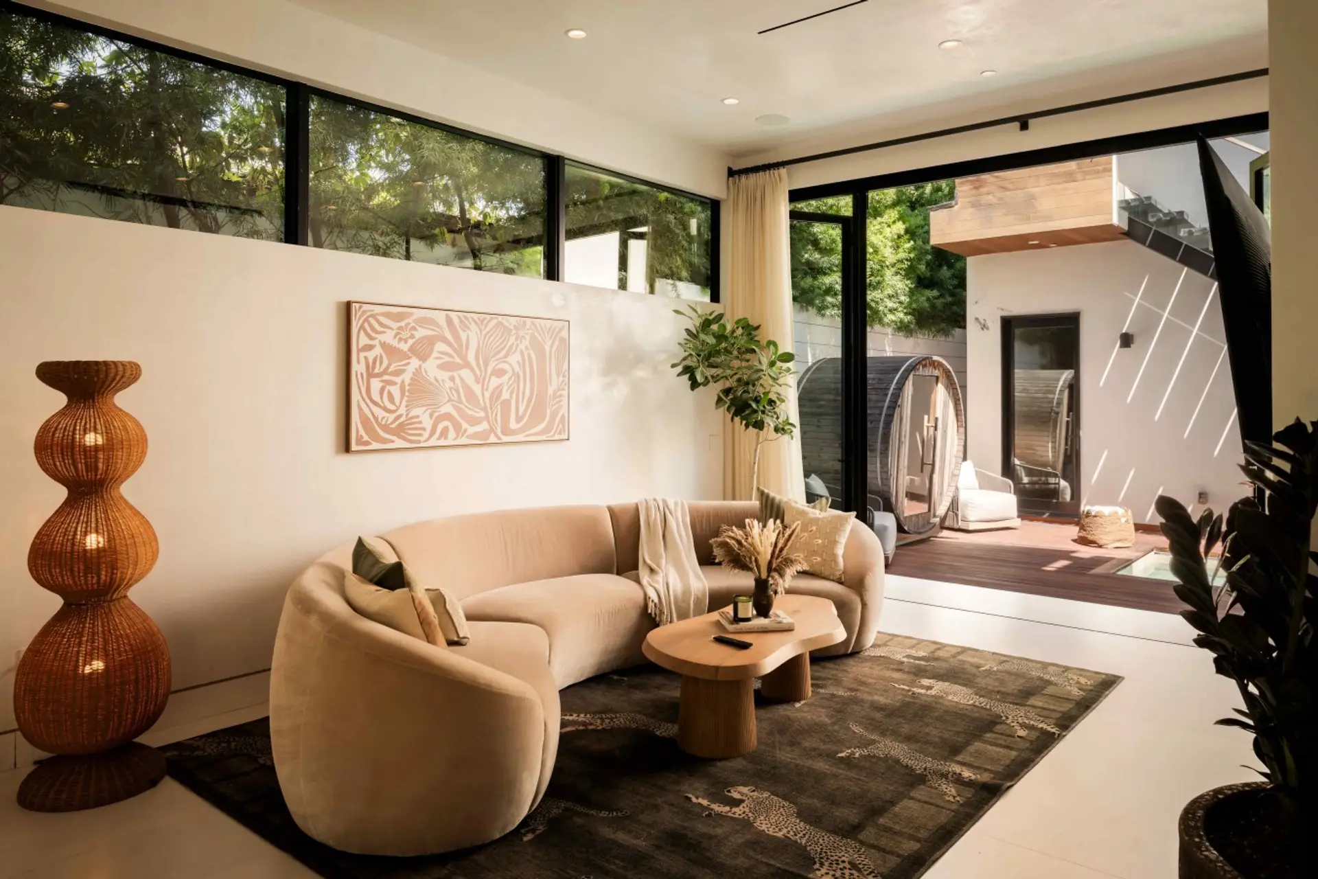 A curved, plush sectional invites cozy nights in, while pocket doors open directly onto a private outdoor plunge pool and cedar sauna. Bold artwork, a sculptural rattan floor lamp, and a leopard-print rug add personality to this laid-back yet elevated lou