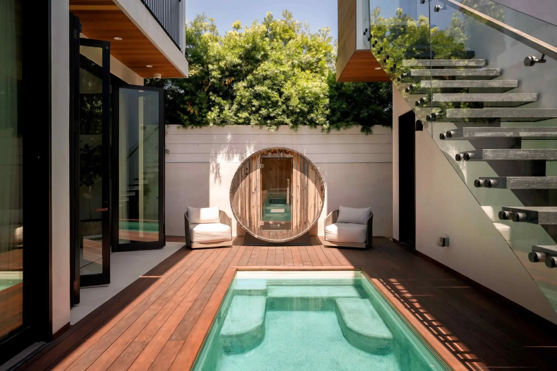 Wood decking, a cozy plunge pool, and a rustic barrel sauna make this backyard feel like a private spa.