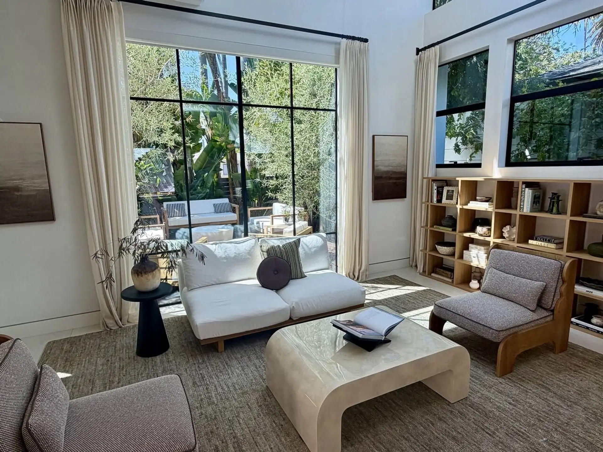 A striking double-height living room where indoor and outdoor blur together, surrounded by trees on every side.