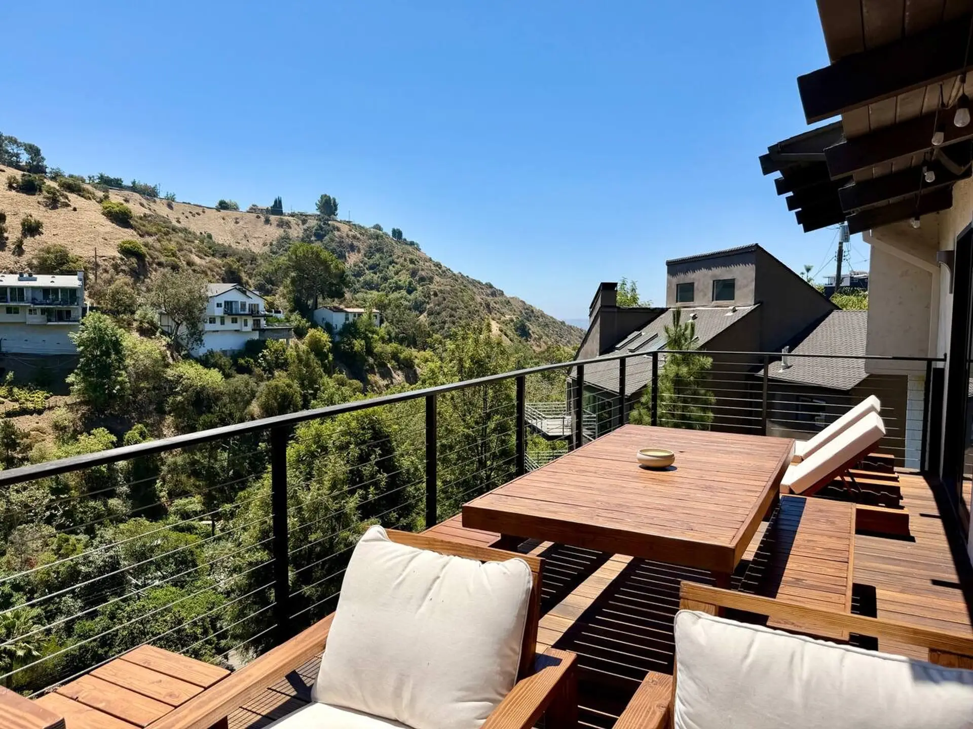 The deck extends the living space outdoors, with a large sofa and dining table.