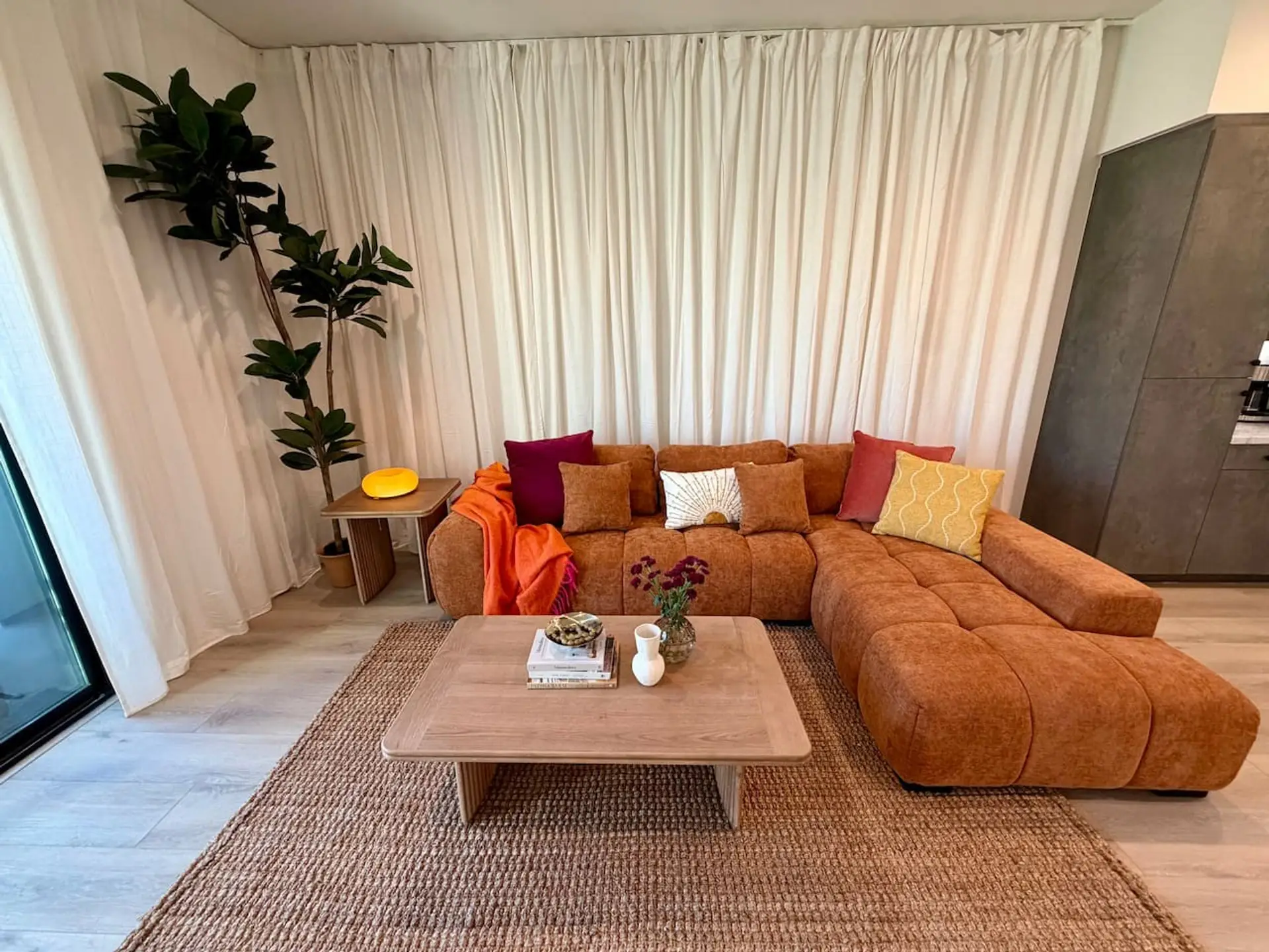 Rust-toned sectional and jute rug set the tone for easy gathering in the main living space.