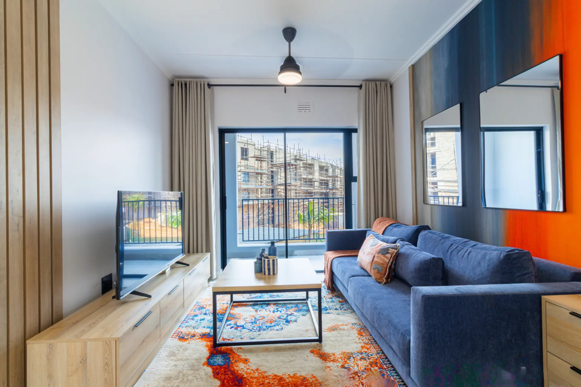 Spacious open-plan living room with smart TV and sliding doors to private balcony.