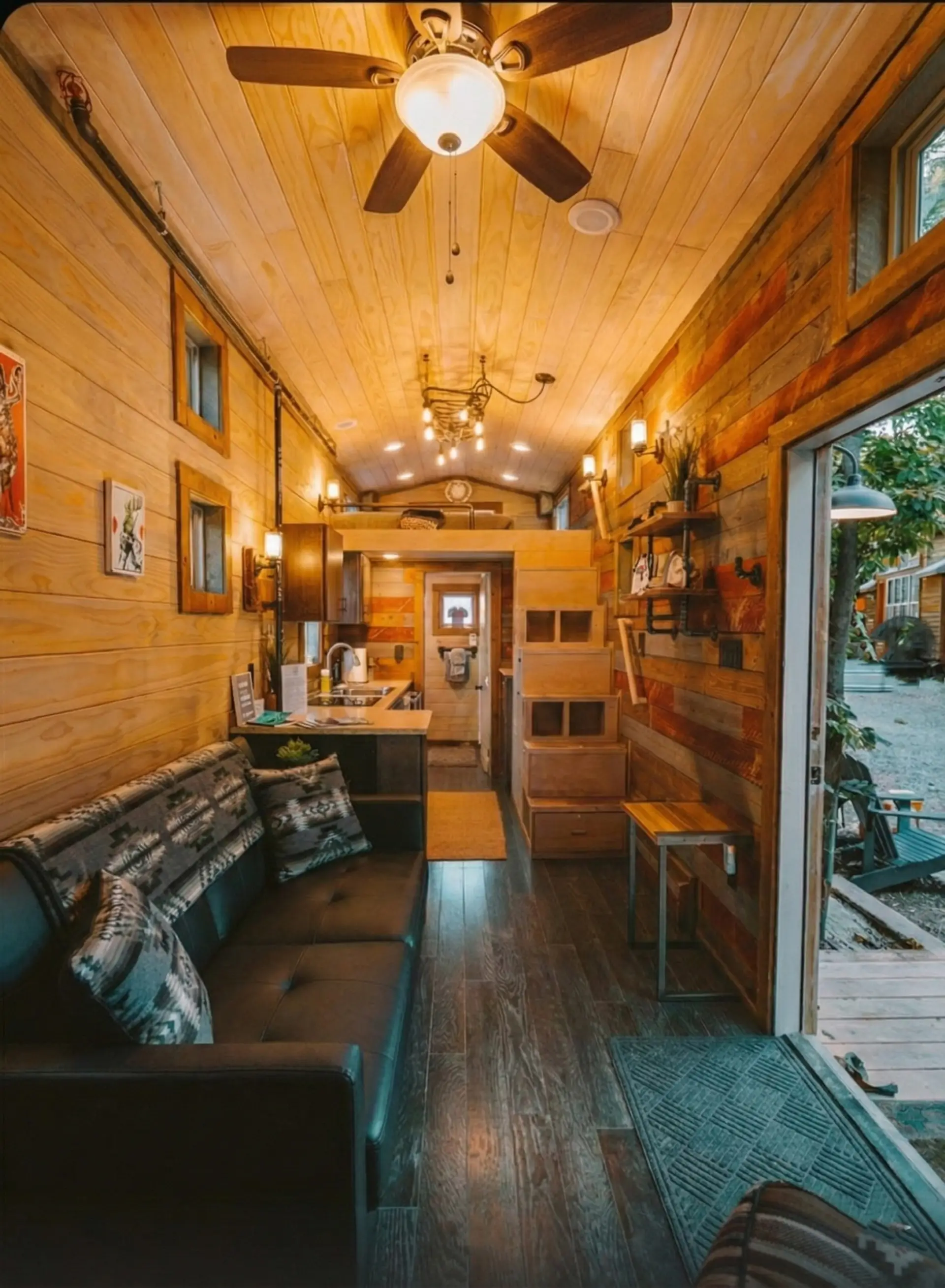 Leather sofa seating, a fully equipped kitchen, and built-in storage stairs make this tiny home surprisingly spacious.