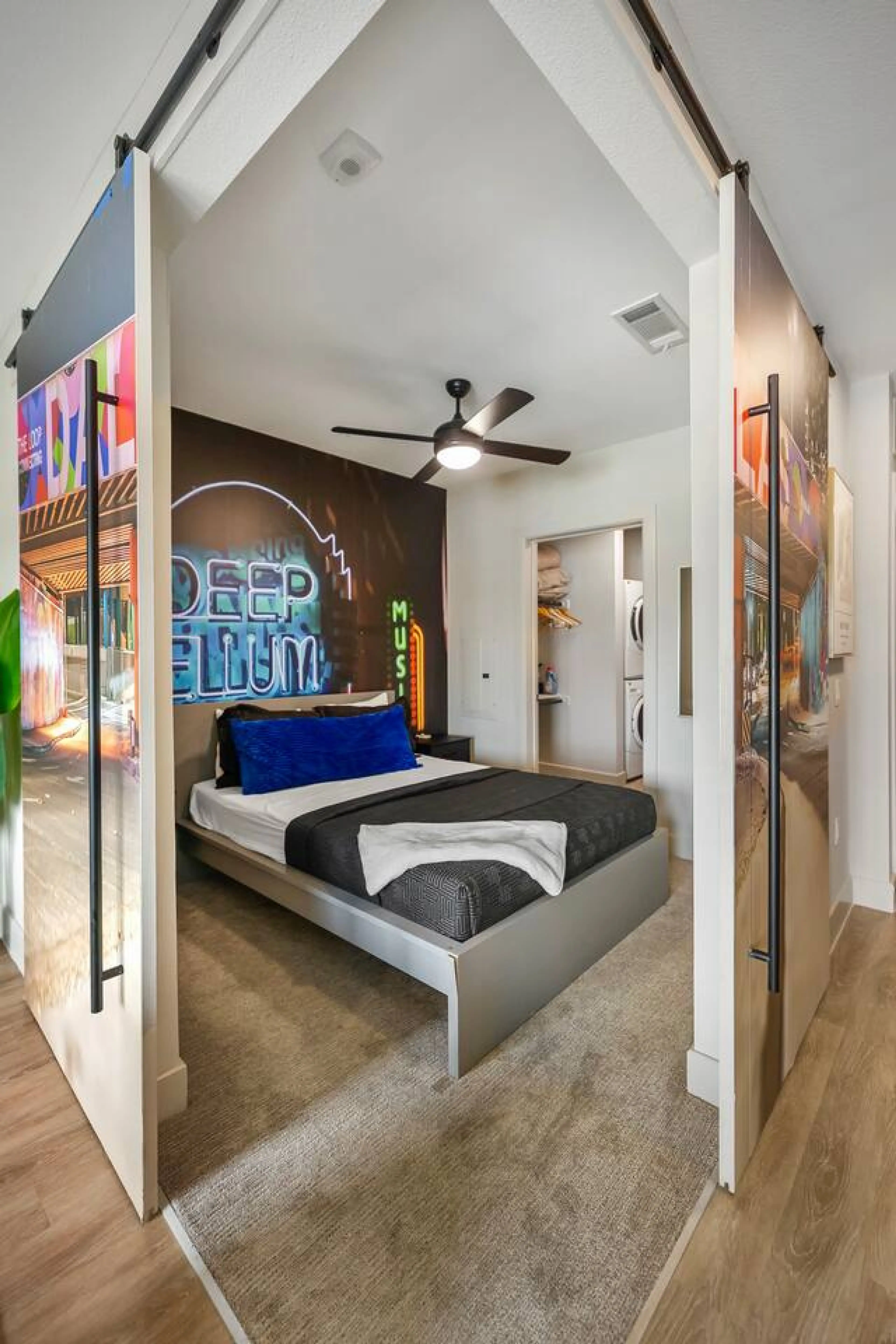 Unwind in serene Queen bedroom dressed in crisp white and grey linens, accented with bold blue touches and a striking Deep Ellum mural for a true loft-style vibe.
