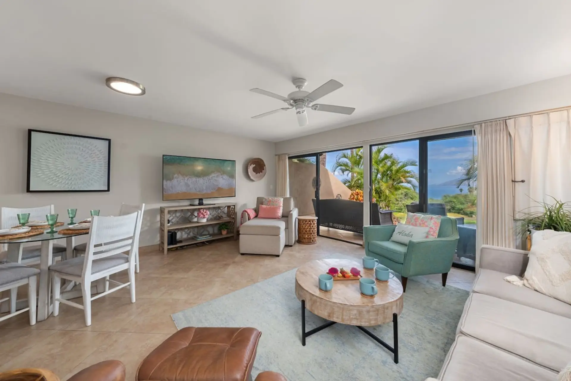 Ocean View Retreat☀️  Relax in a bright, AC-cooled living area with a flat-screen TV and floor-to-ceiling windows. Step out onto the private balcony for lush tropical views just outside your door.
